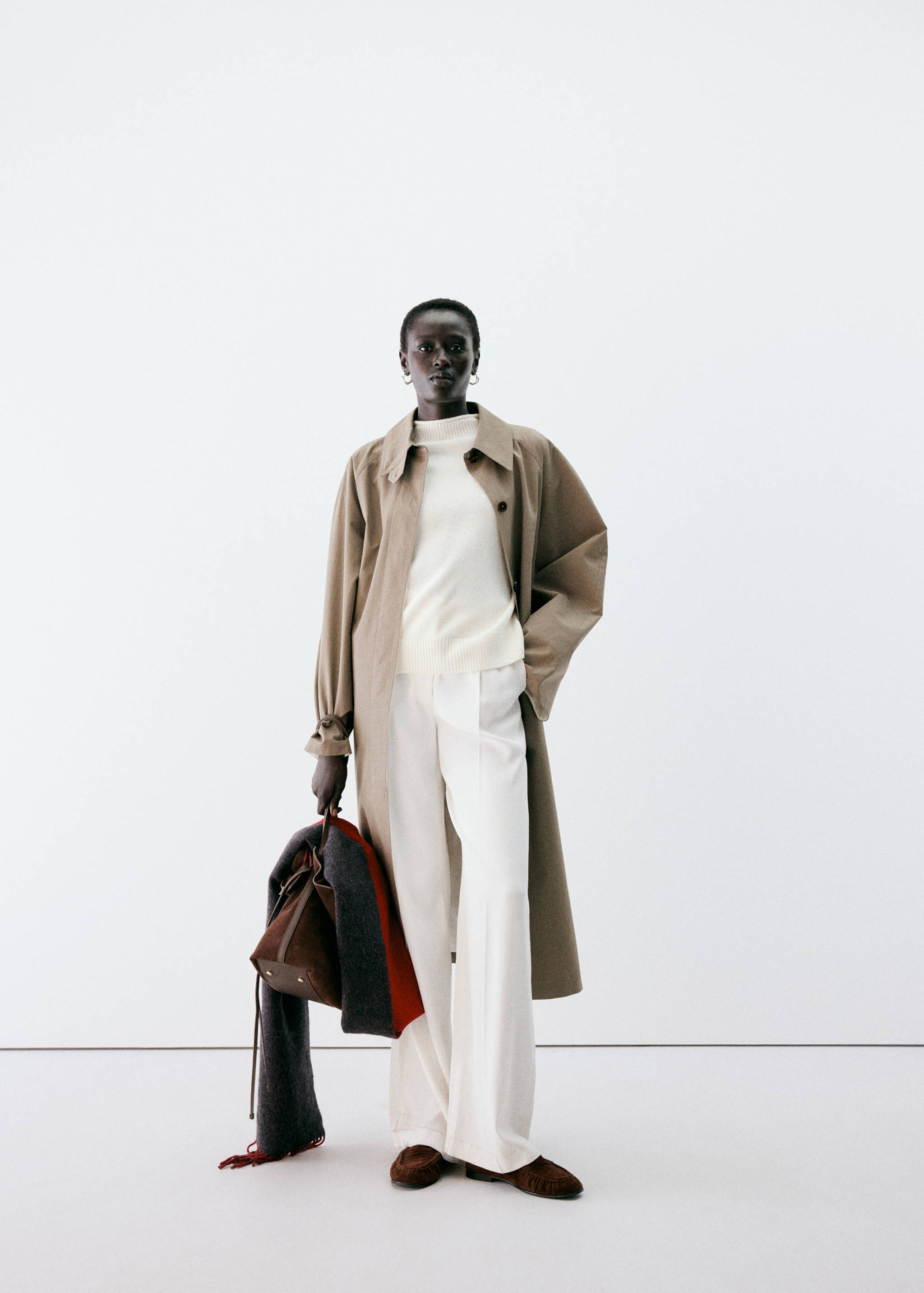 White high-neck knitted jersey worn with a beige trench coat and white trousers.