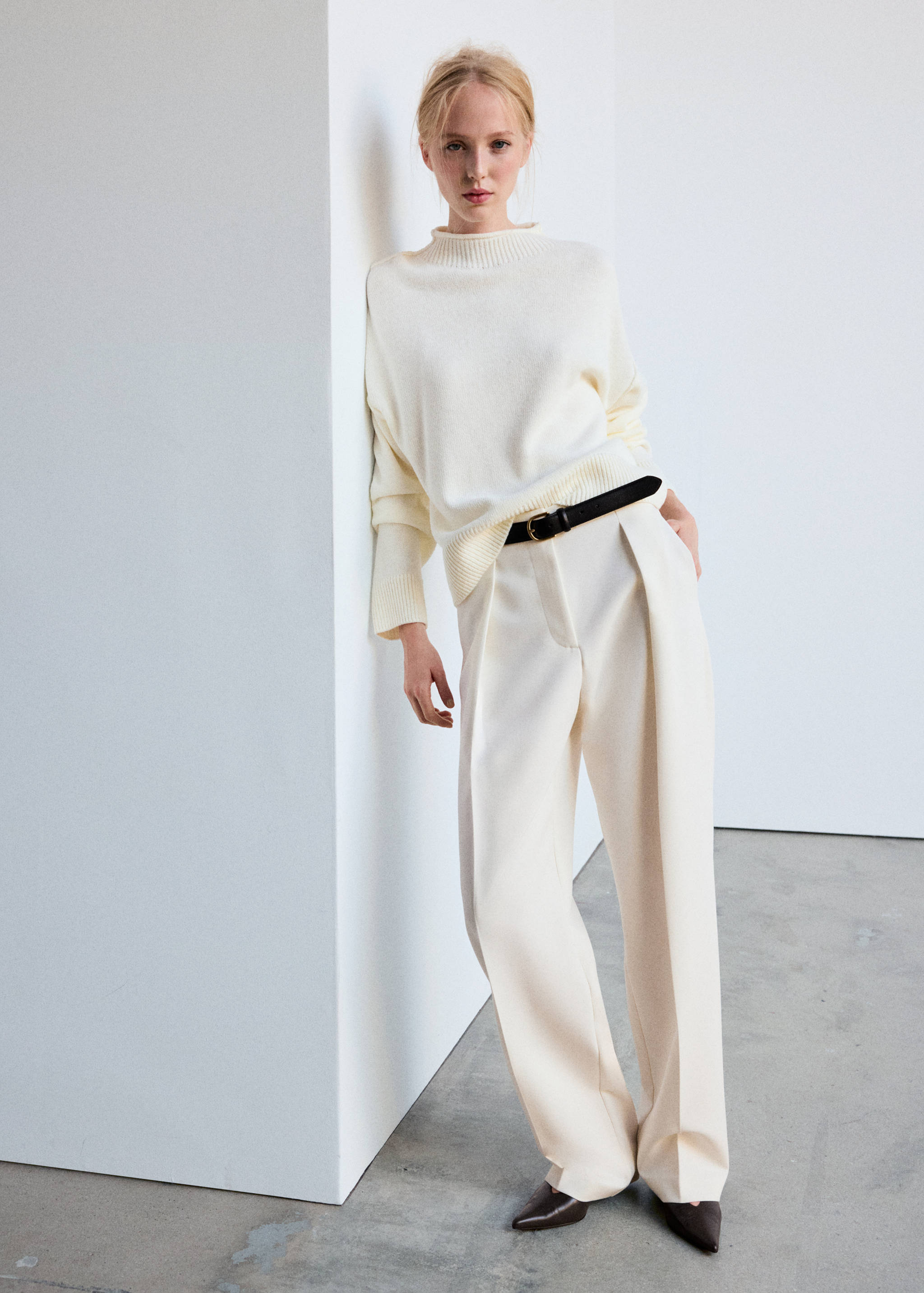 Jersey de punto en color crema con cuello alto de canalé, combinado con unos pantalones anchos a juego.