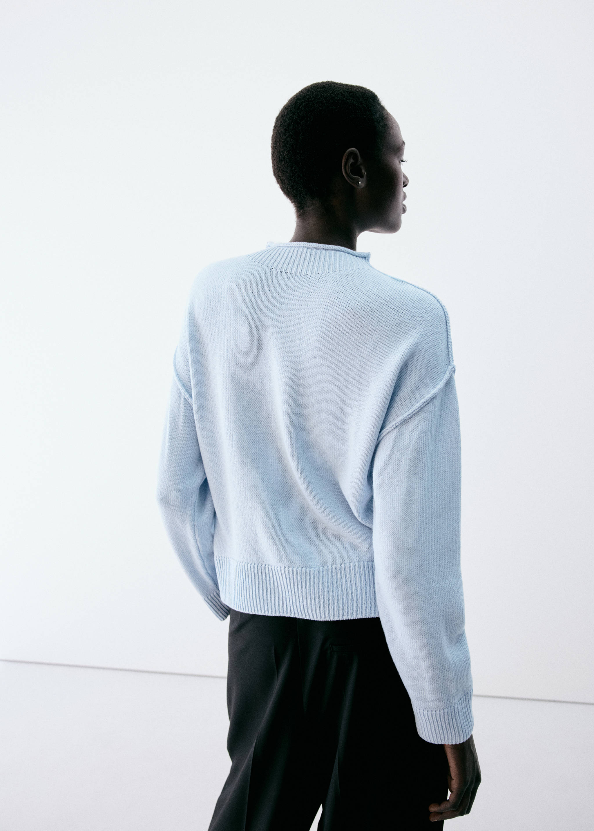 Light blue knitted jersey, back view, featuring a ribbed high neckline.