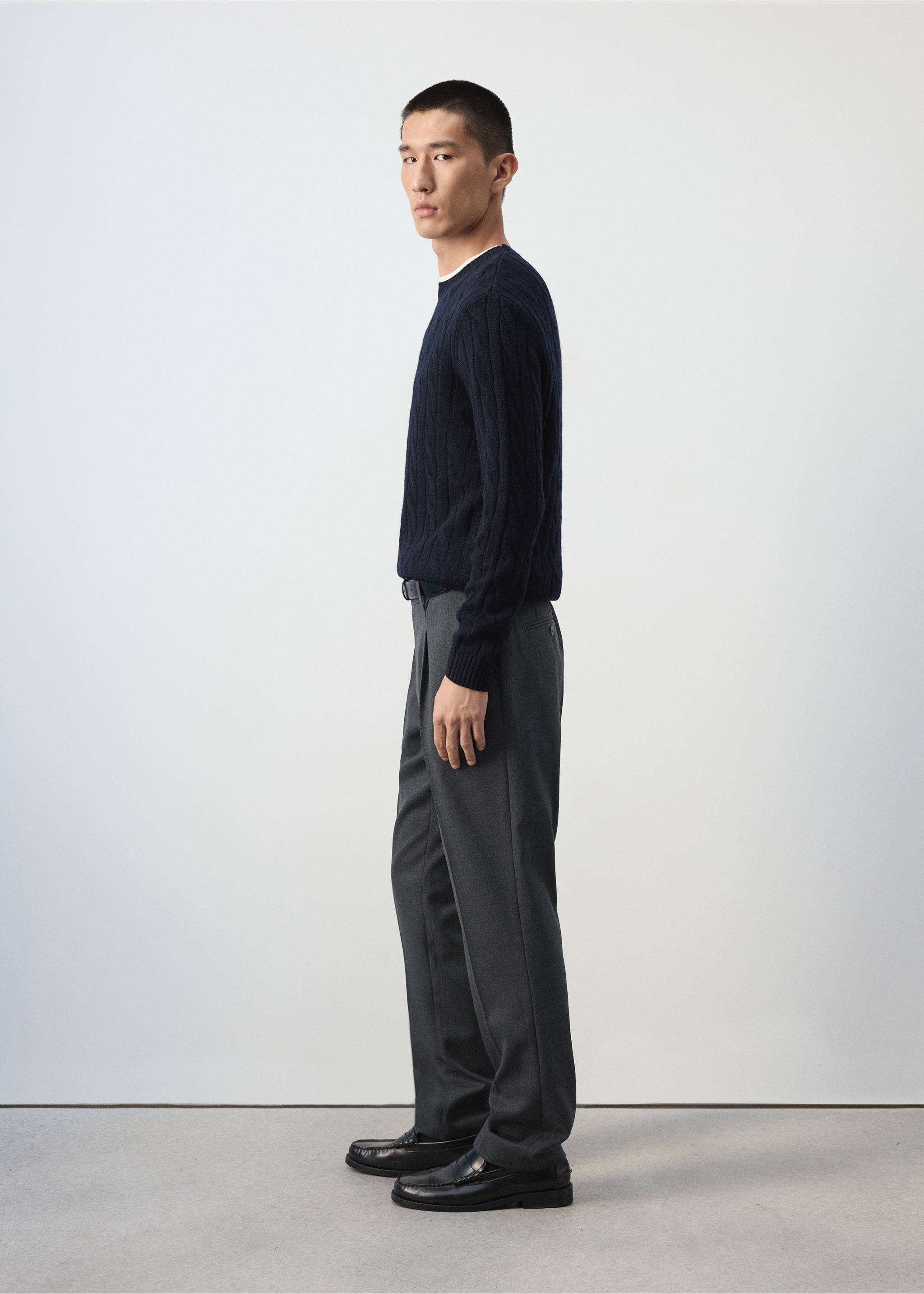 Grey pleated trousers worn with a navy blue cable-knit sweater., Charcoal. Ref: 37007888-00.