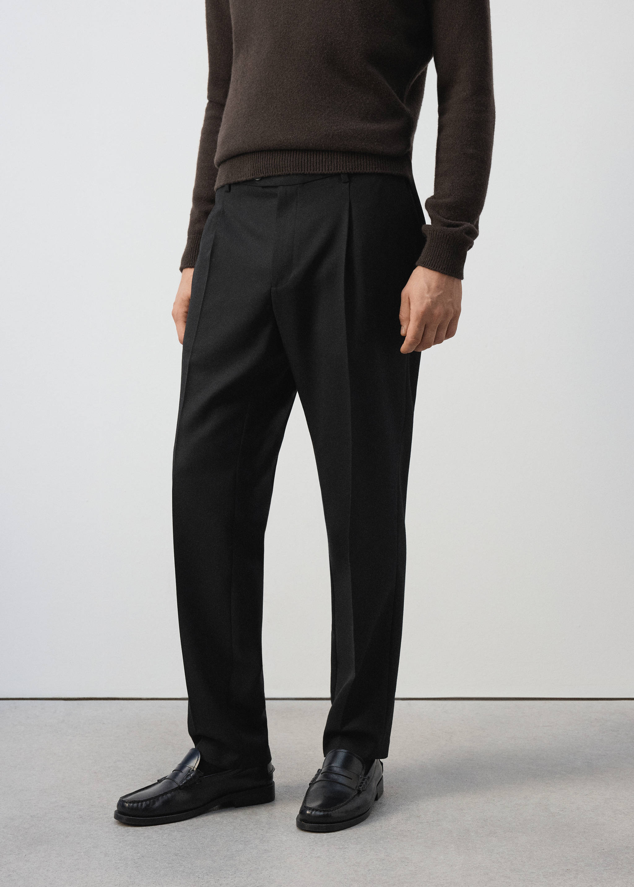 Pantalón de traje negro con pinzas y raya central.