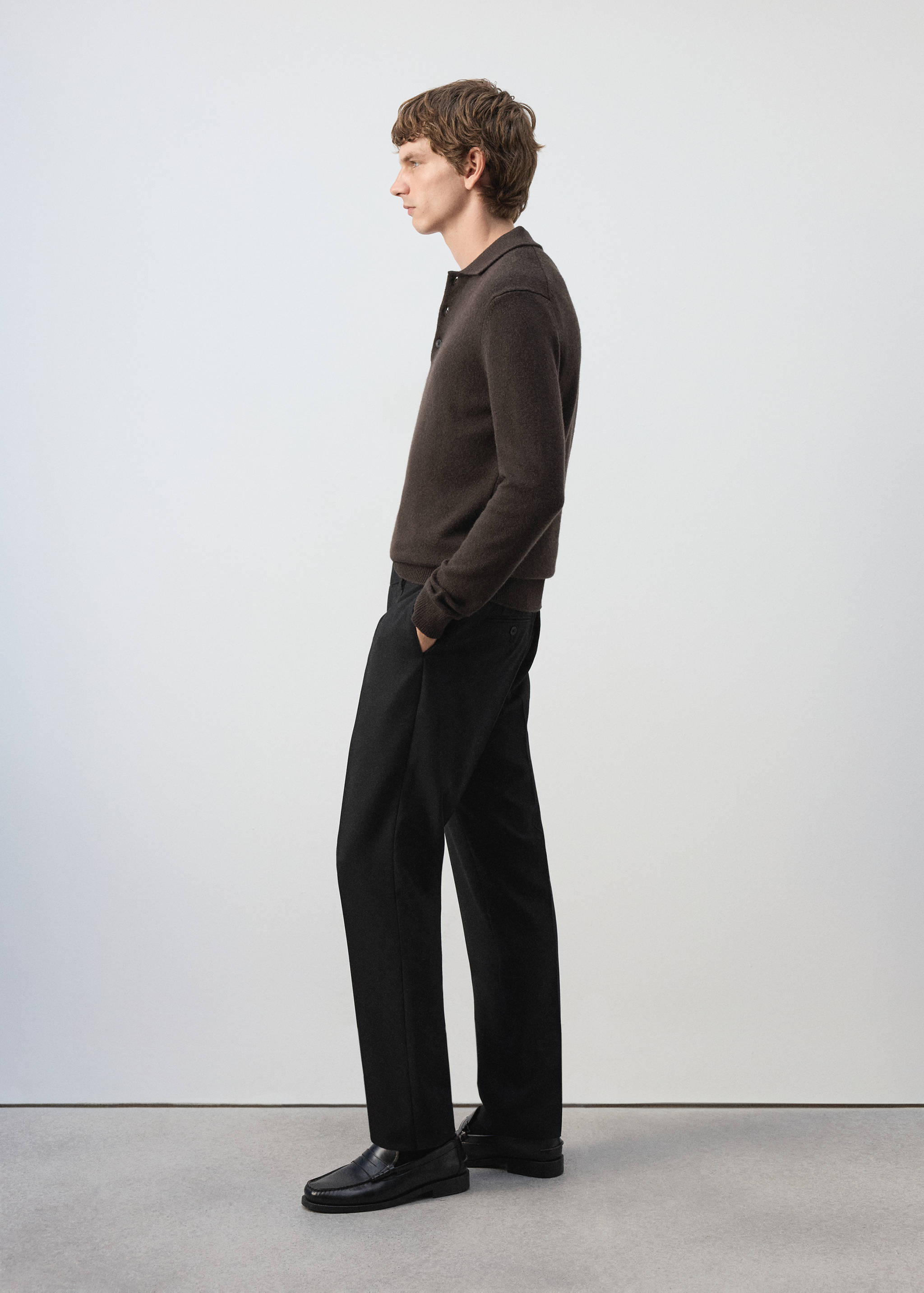 Pantalón negro combinado con un polo marrón oscuro y mocasines.