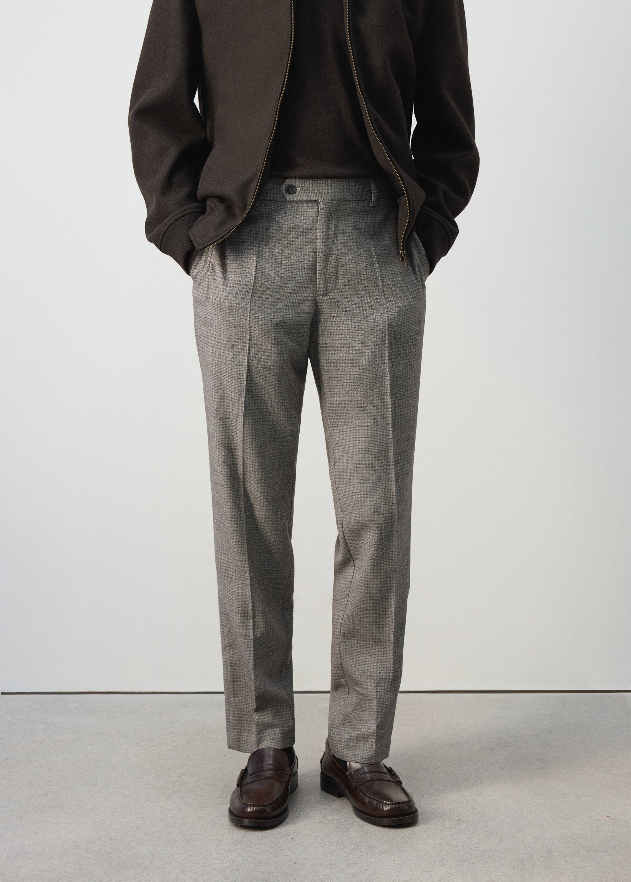 Grey plaid trousers with pleated front and pressed creases.