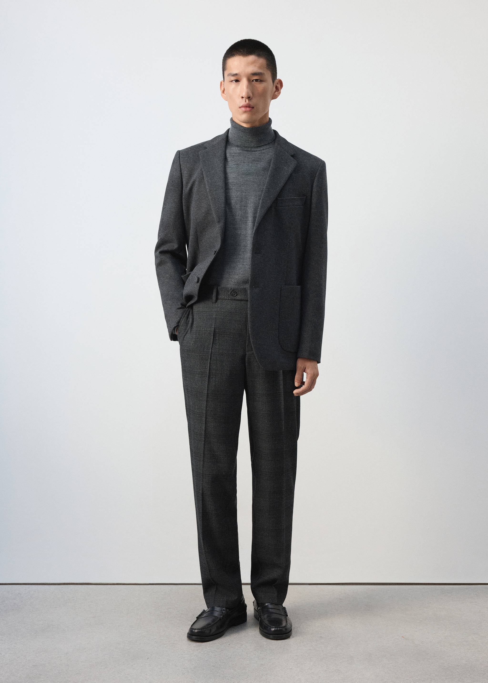 Charcoal grey check trousers worn with a matching blazer, turtleneck, and black loafers.