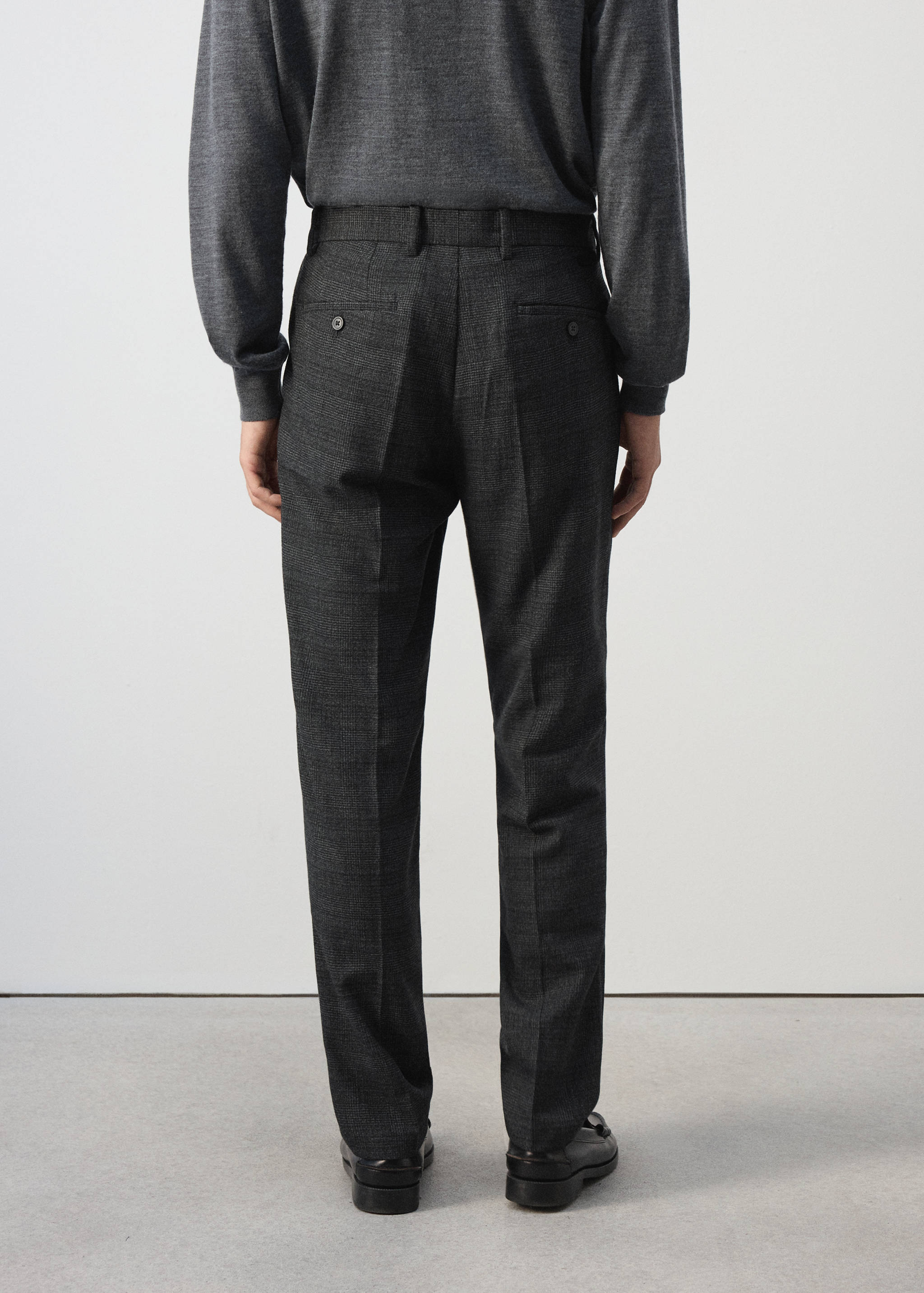 Dark grey trousers seen from the back, featuring belt loops and back welt pockets.