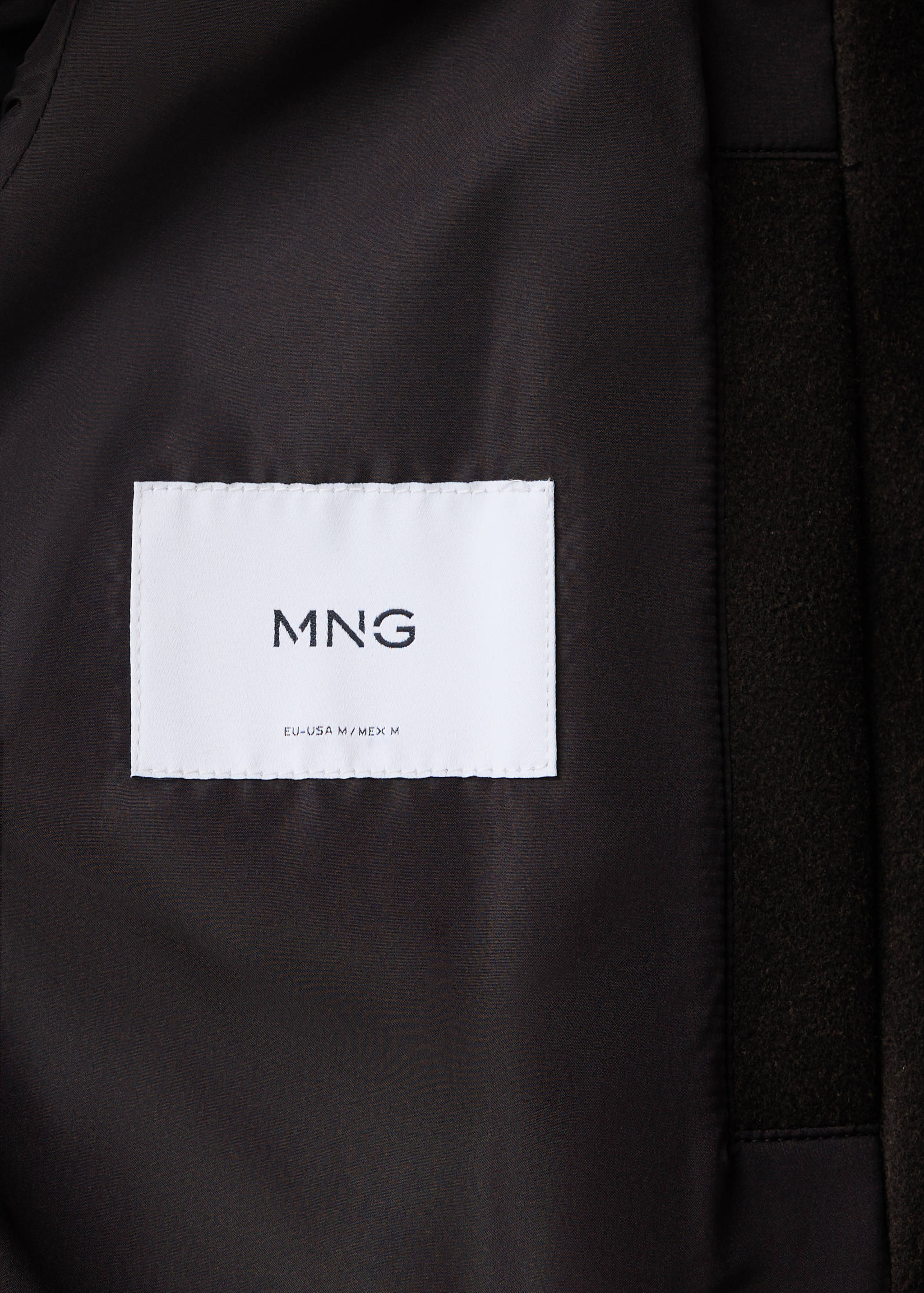 Close-up of the interior fabric and brand label of a dark brown jacket.