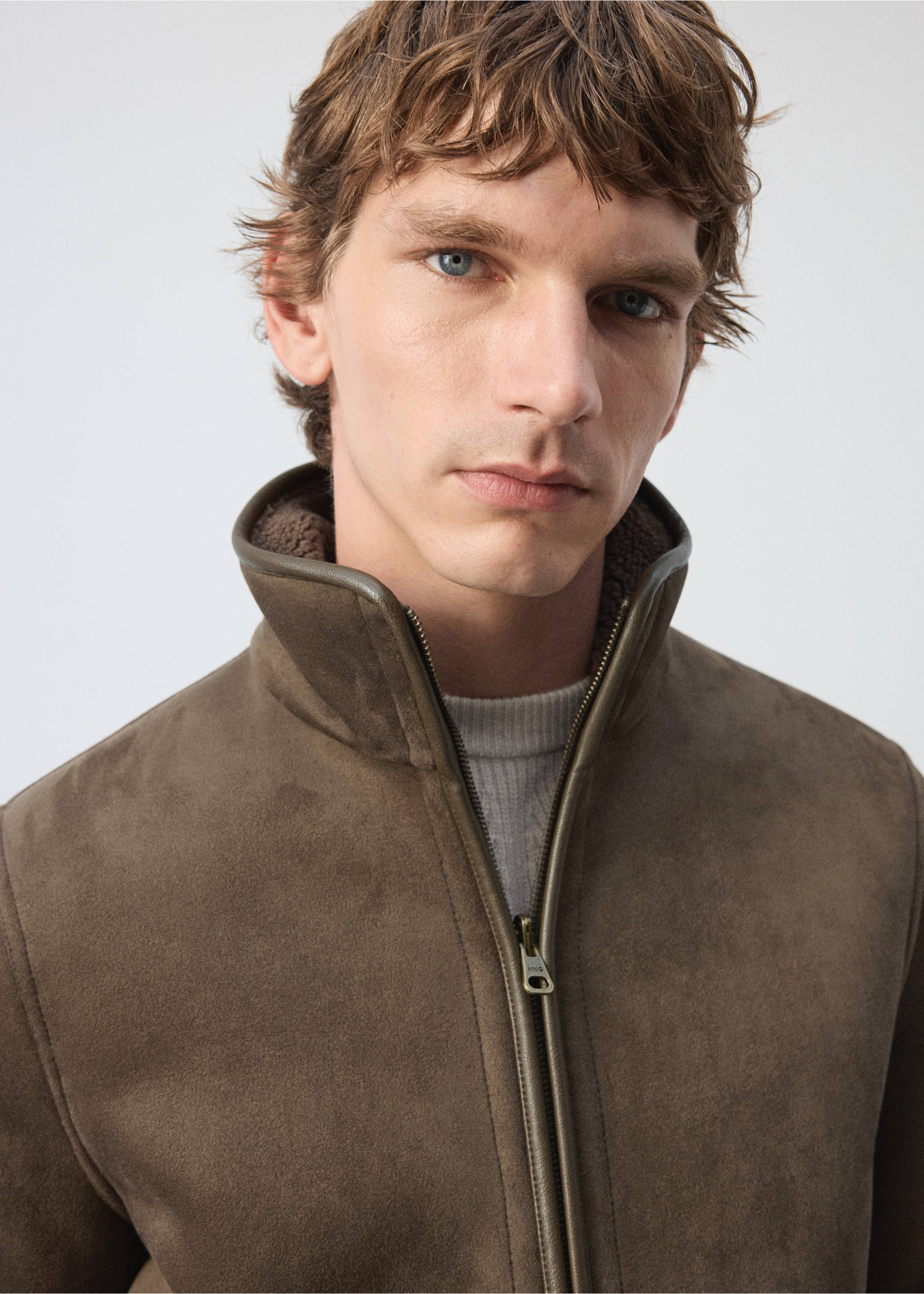 Close-up of an olive green faux-shearling jacket with a high funnel collar and zip fastening worn by a model., Olive Green. Ref: 37007894-00.
