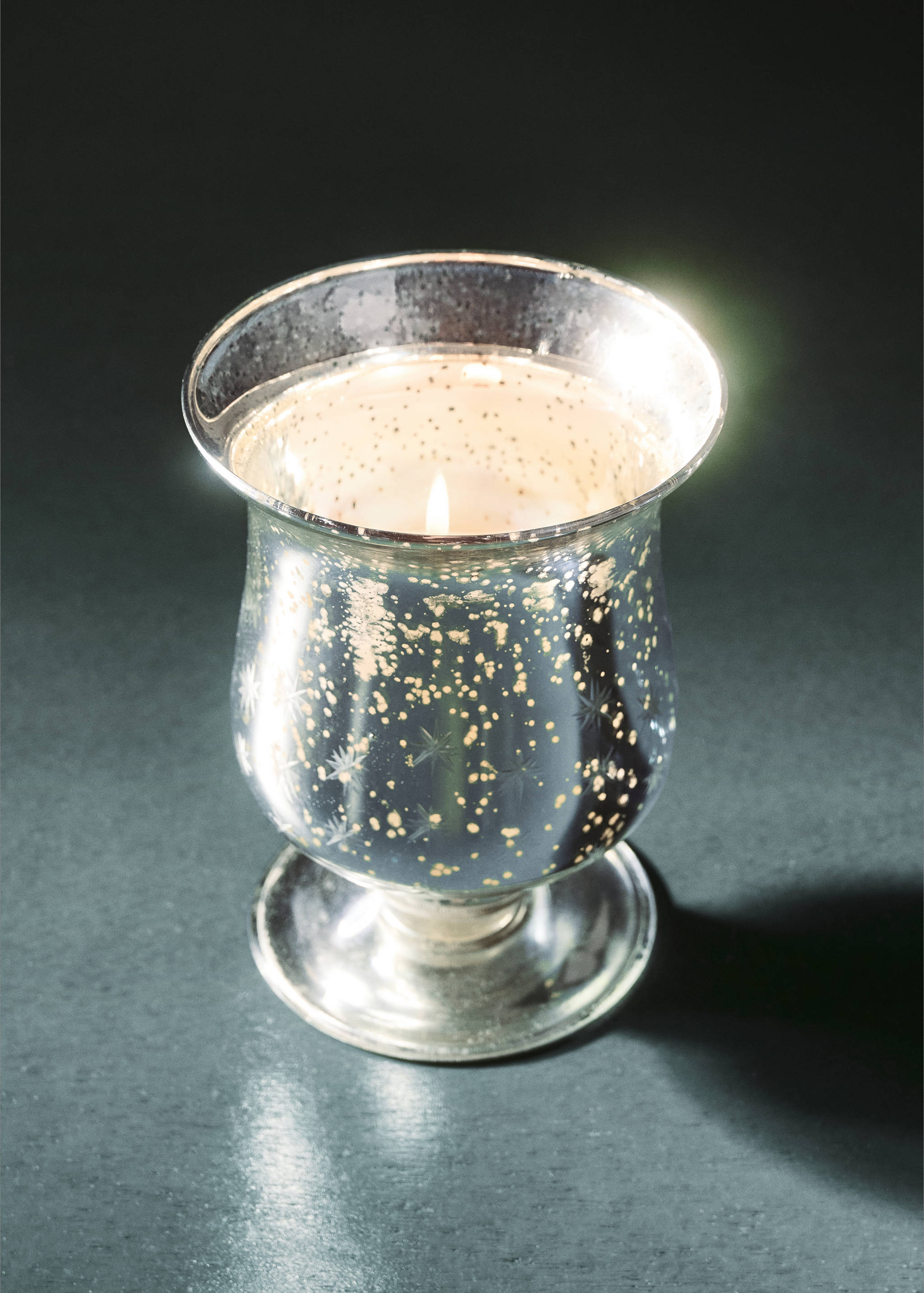 Lit candle holder in speckled silver and gold glass.