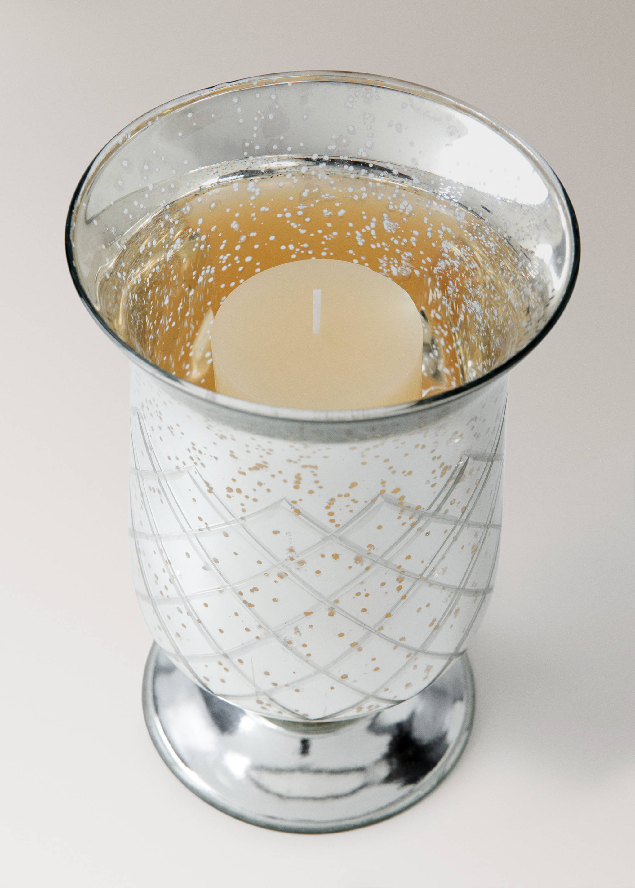 Speckled glass candle holder with a geometric pattern and a pillar candle inside.