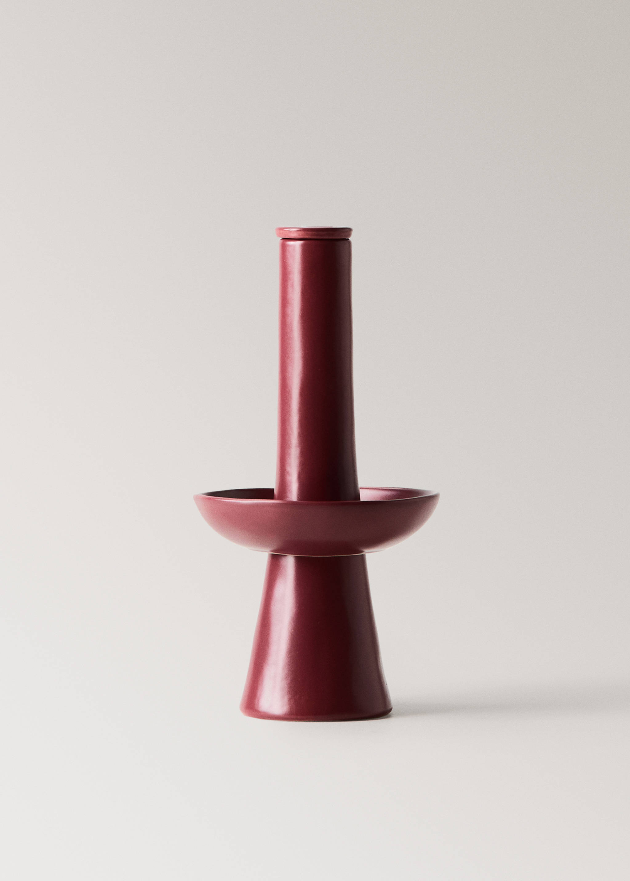 Burgundy ceramic sculptural candle holder with a flared base and central drip tray.