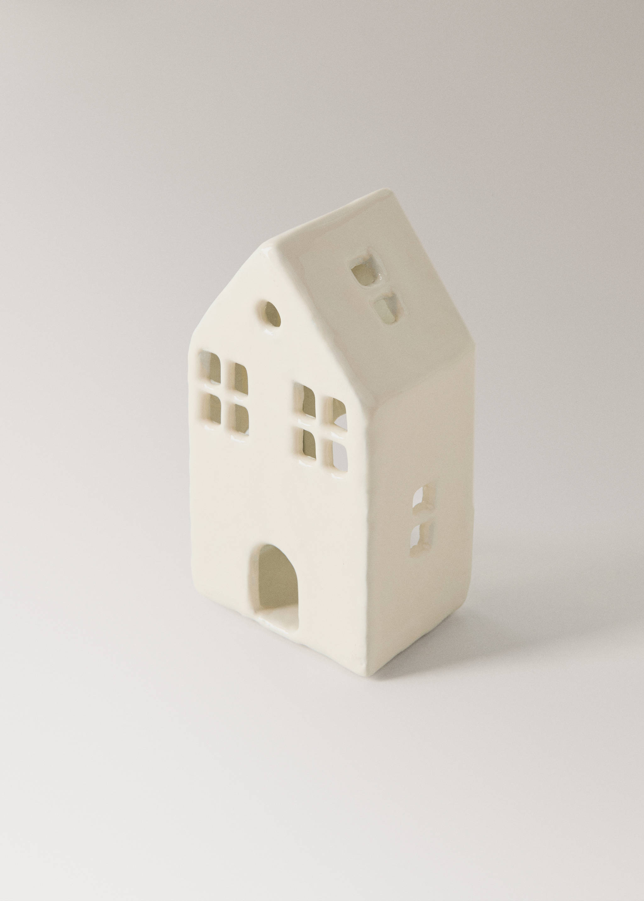 House-shaped white ceramic candle holder with cut-out windows.