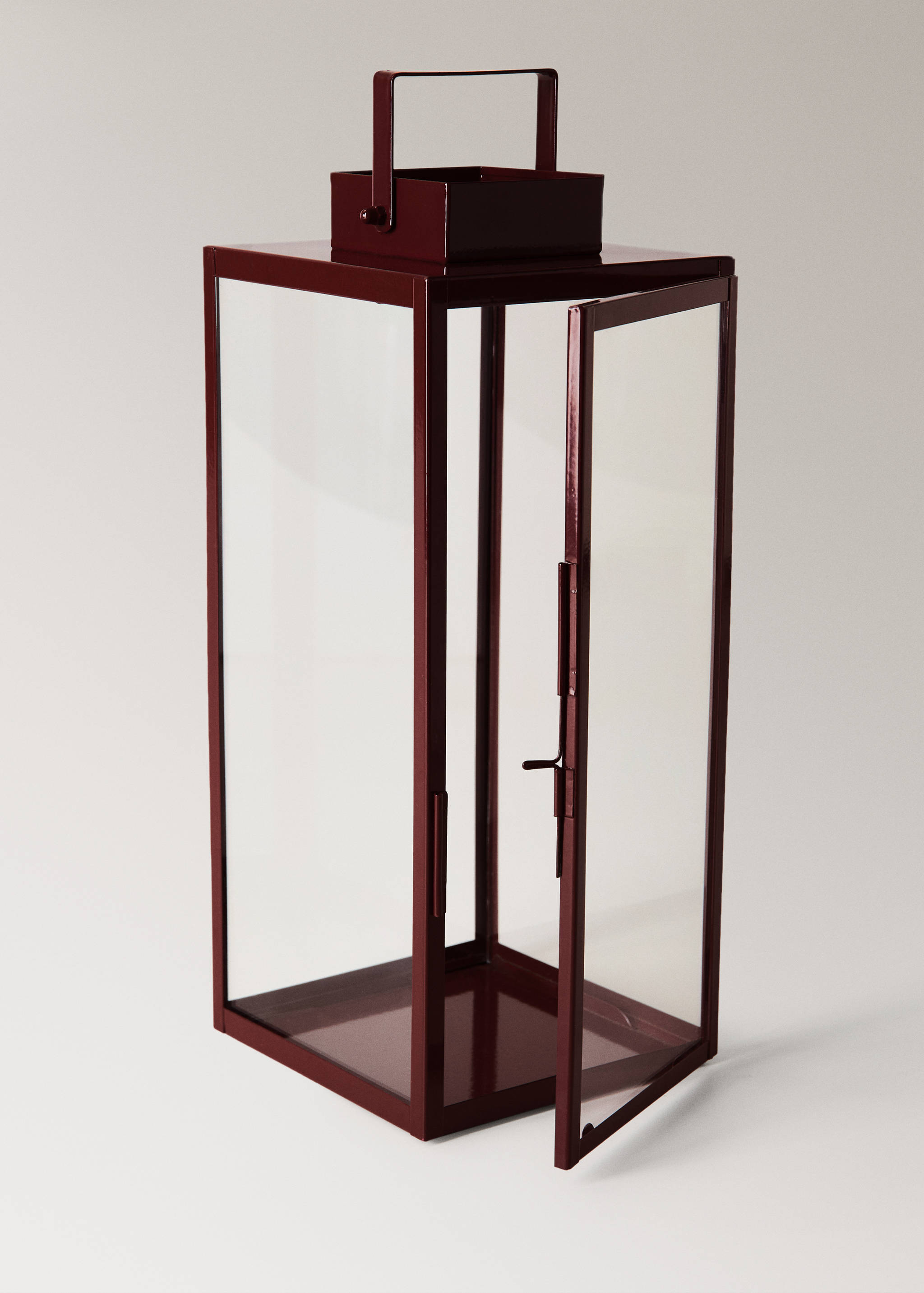 Dark burgundy metal and glass candle lantern with an open side door.
