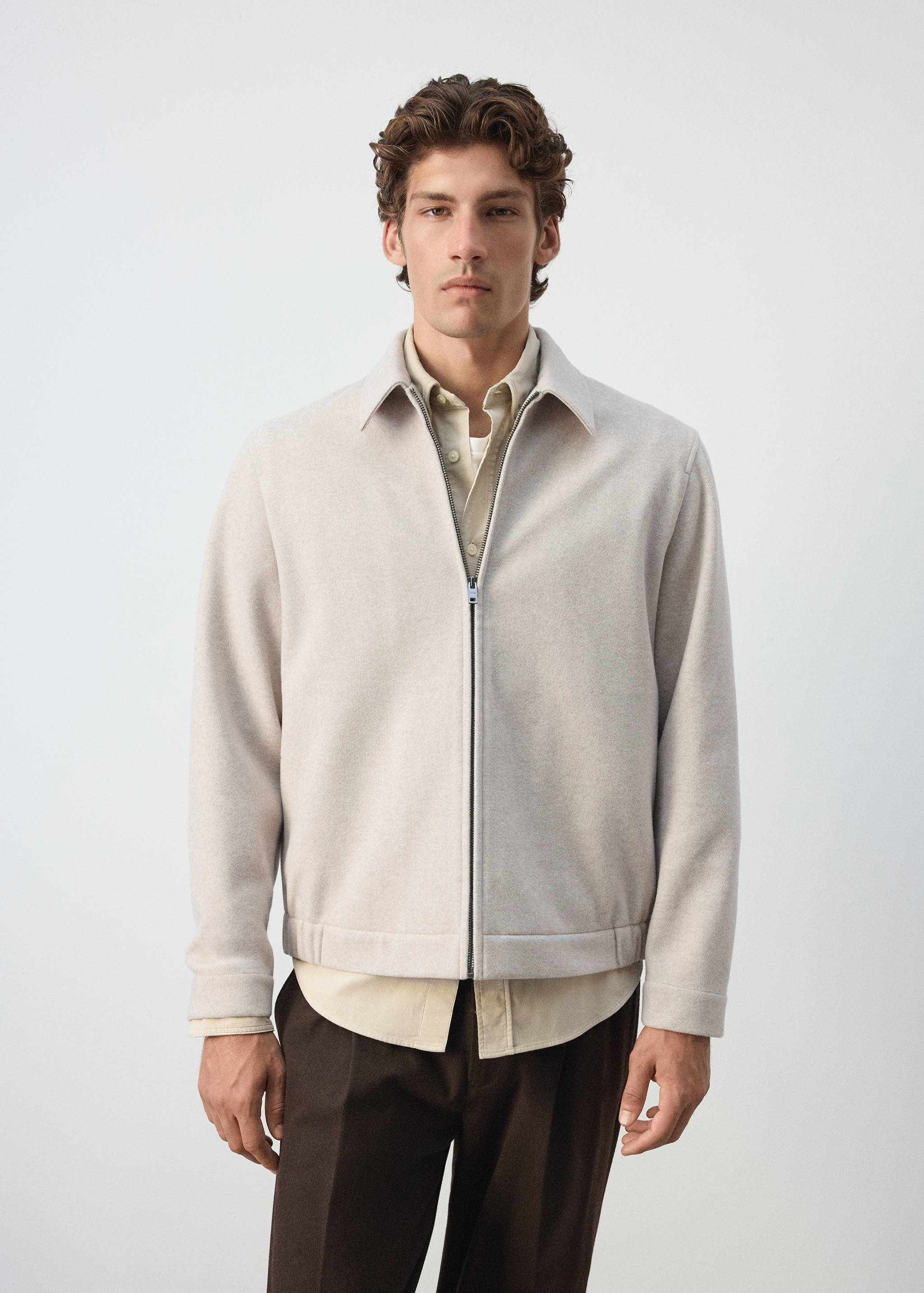 Light beige zip-up sweatshirt with a classic collar worn with a shirt and trousers.