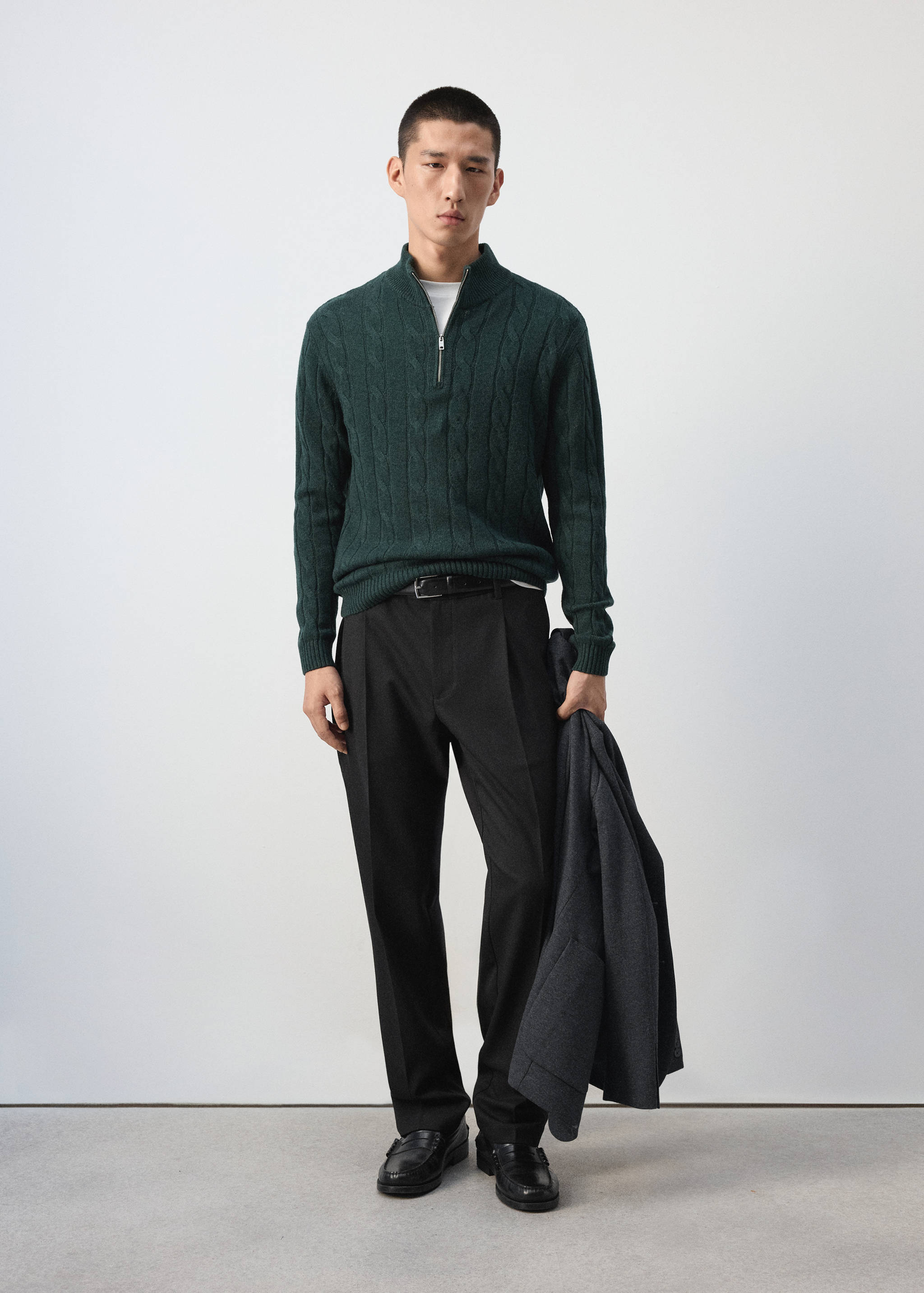 Dark green cable-knit zip-neck jersey worn with dark trousers.