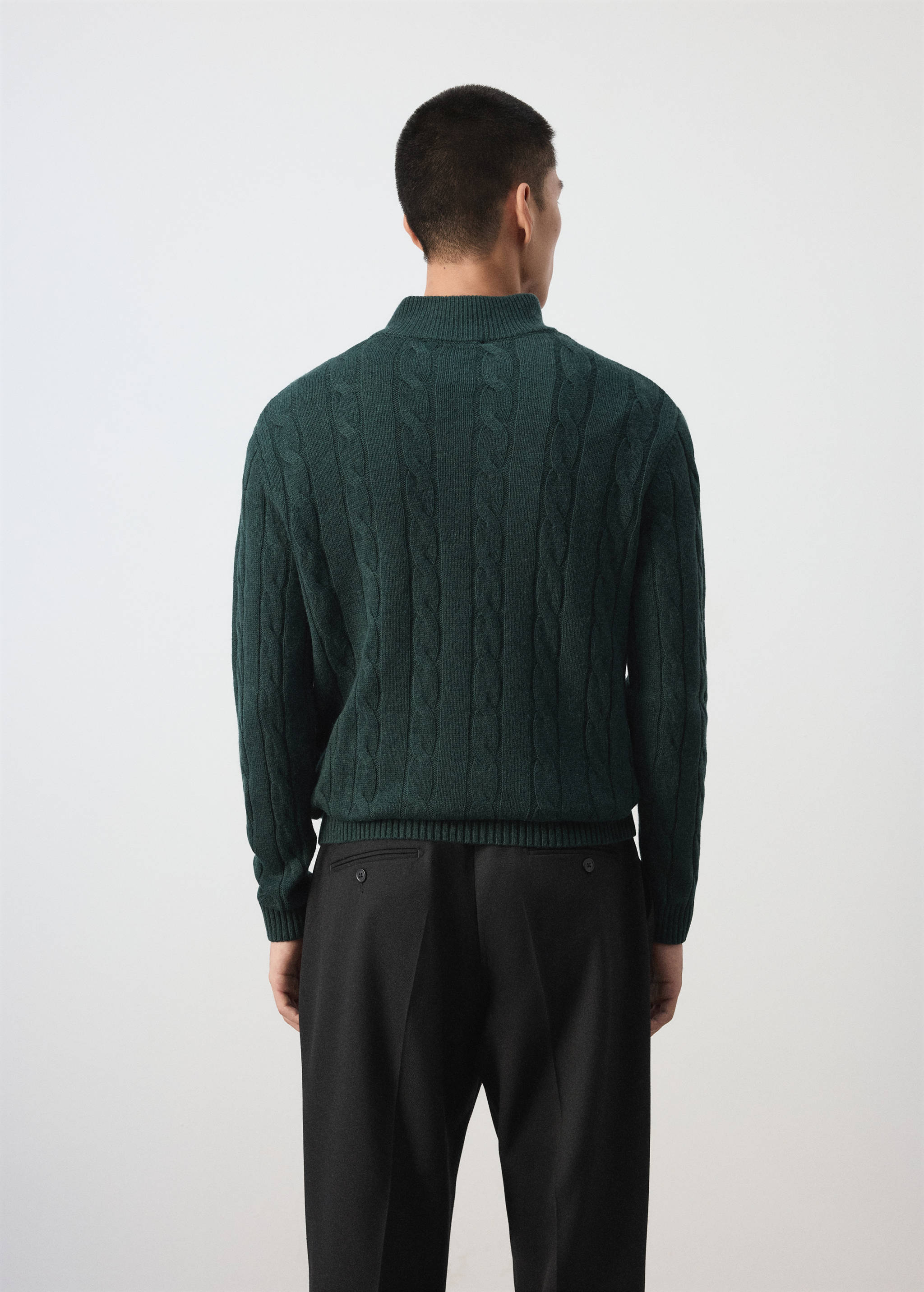 Dark green cable-knit jersey seen from the back.