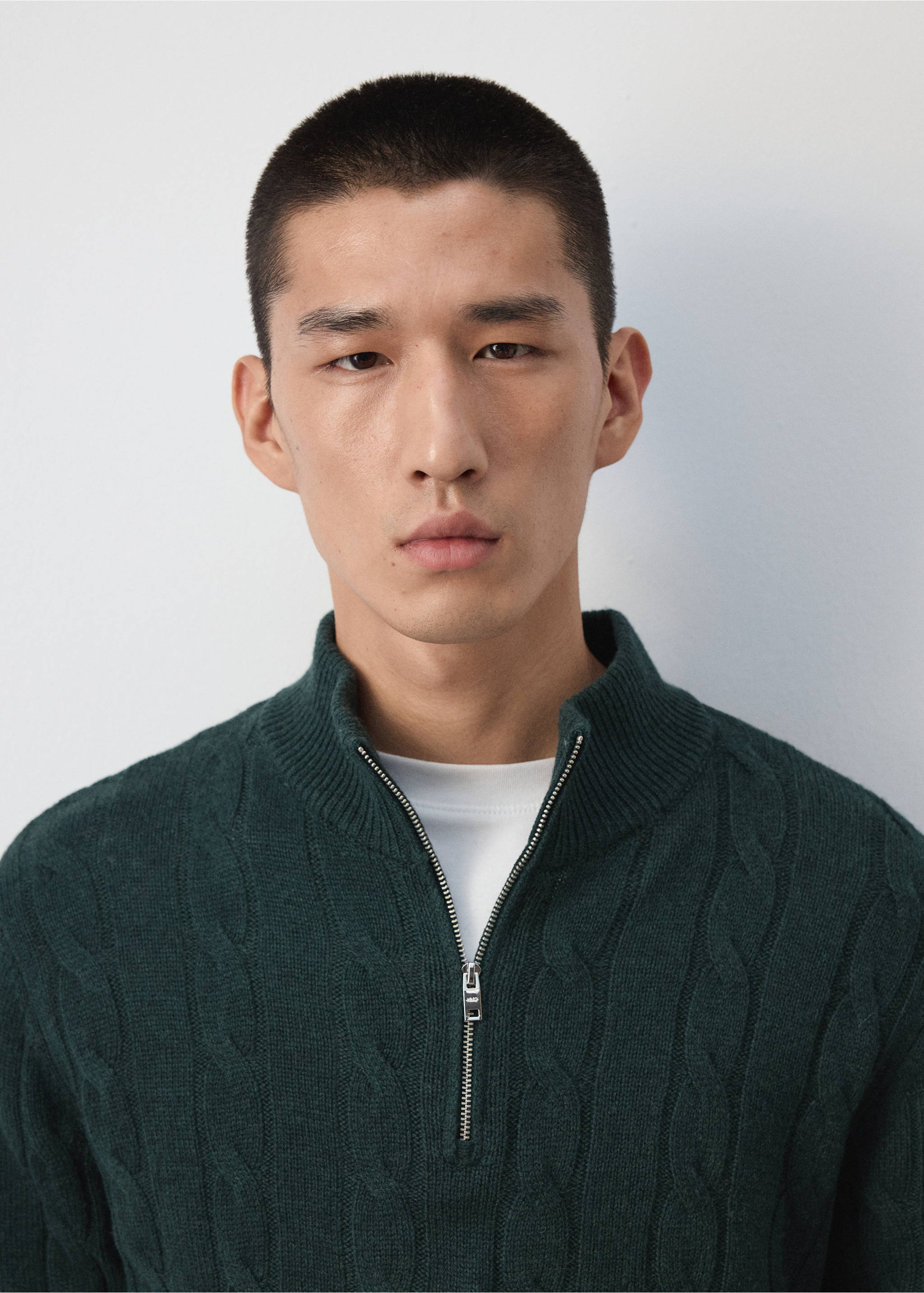 Close-up of a dark green cable-knit zip-neck sweater worn by a model., Dark Green. Ref: 37007921-00.