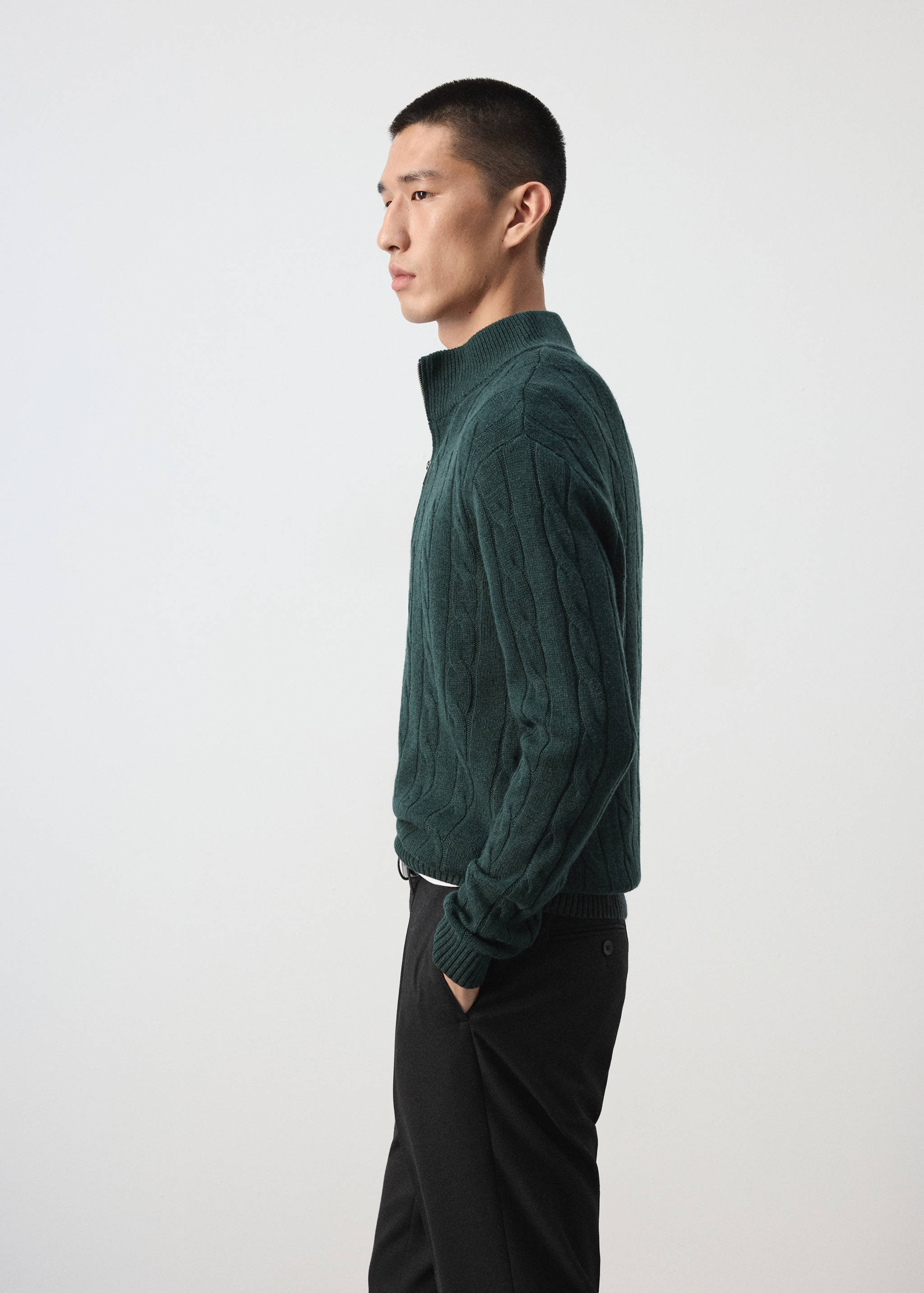Dark green cable-knit half-zip jersey in profile view.