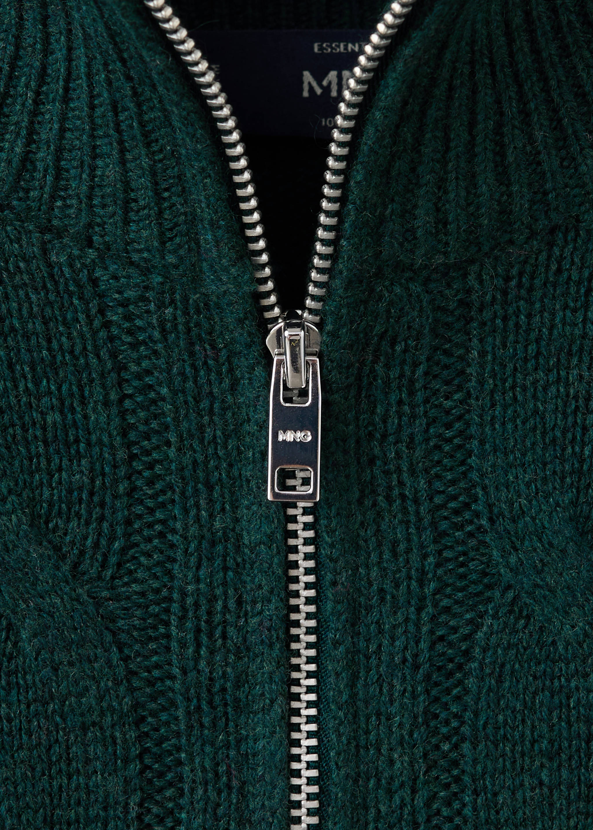 Close-up of a dark green knit jersey featuring a silver-toned metal zip pull.