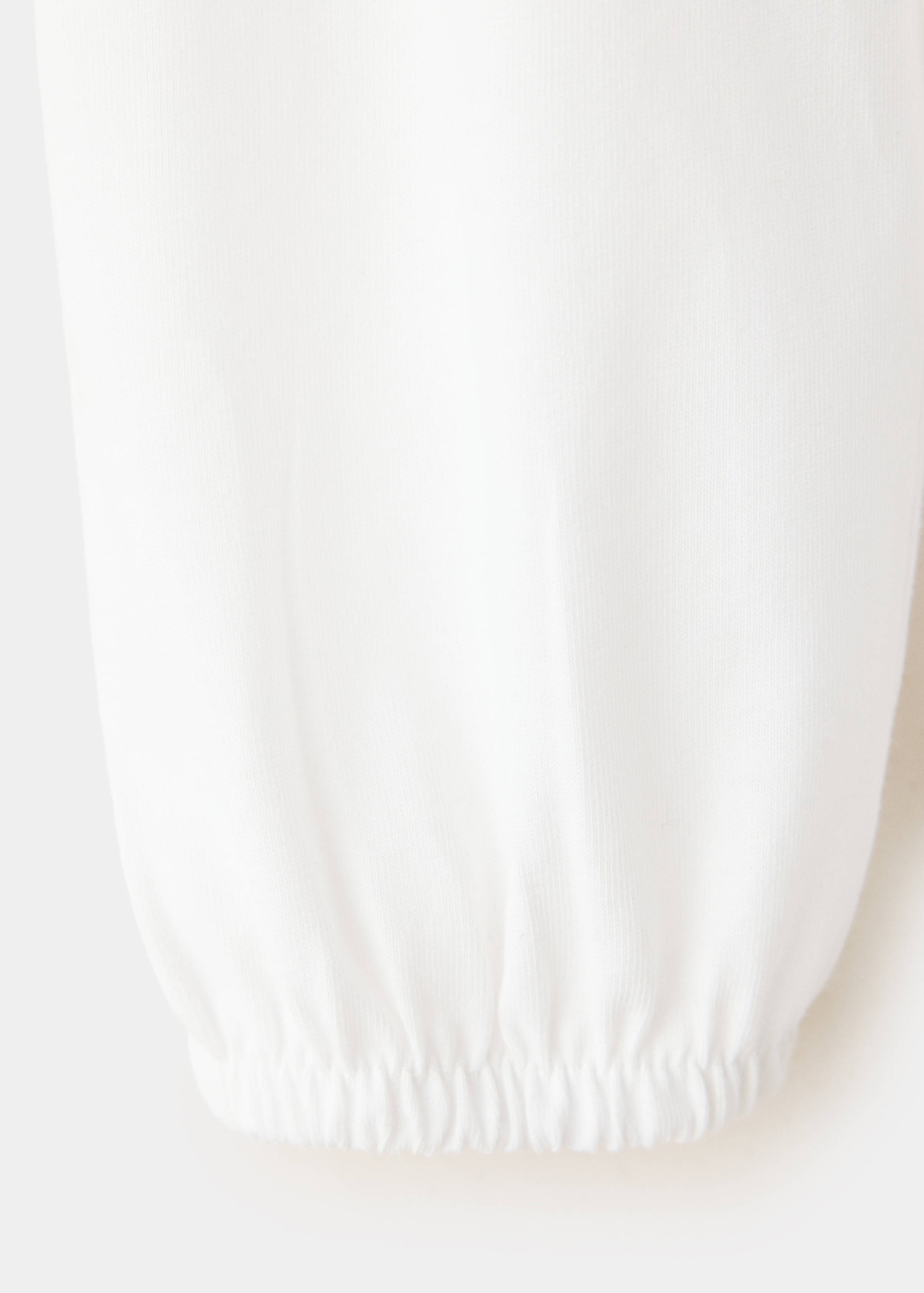Close-up of the white t-shirt fabric and elasticated cuff.