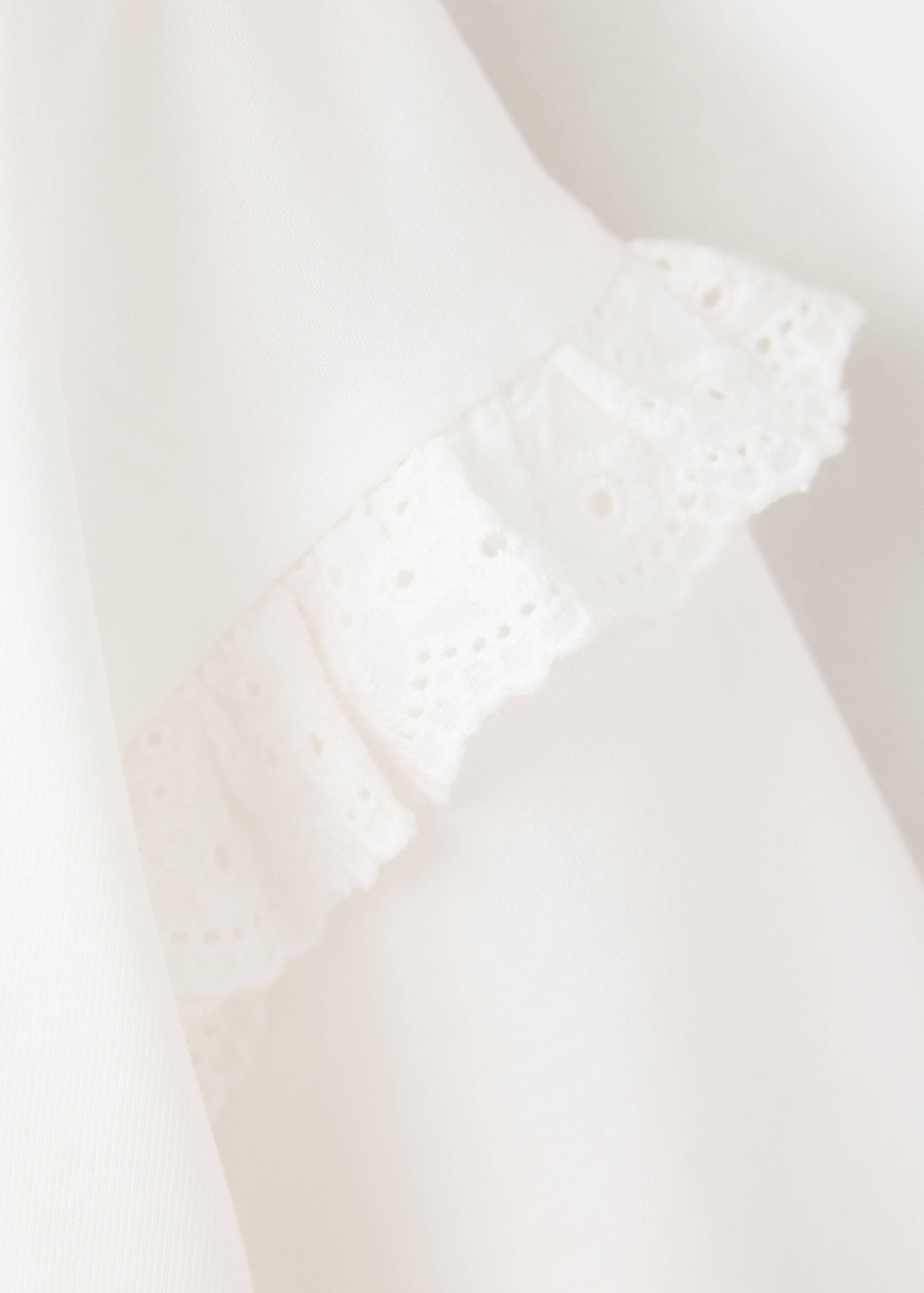 White t-shirt fabric detail with an eyelet embroidery ruffle.