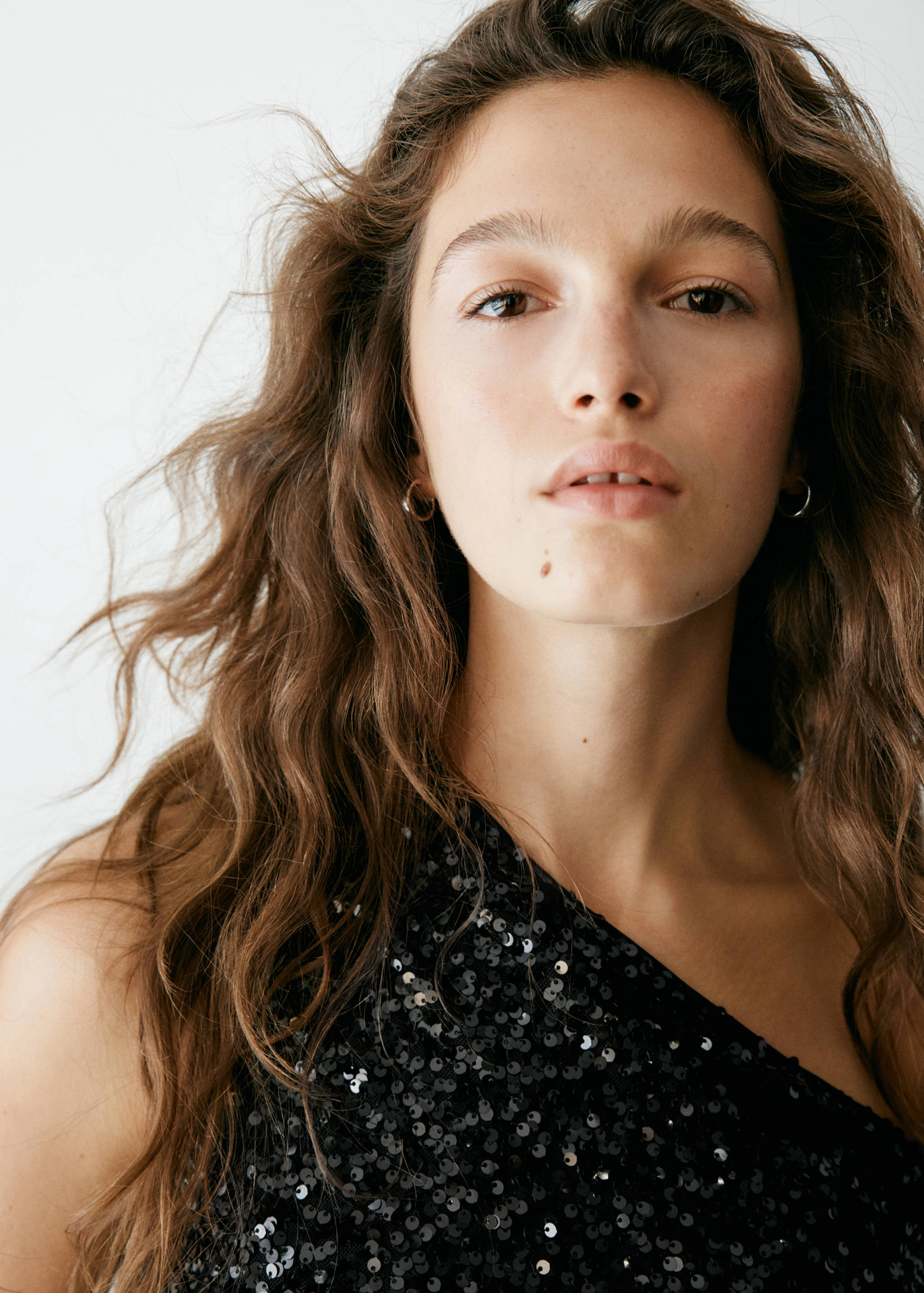 Close-up of a model wearing a black sequinned one-shoulder top.