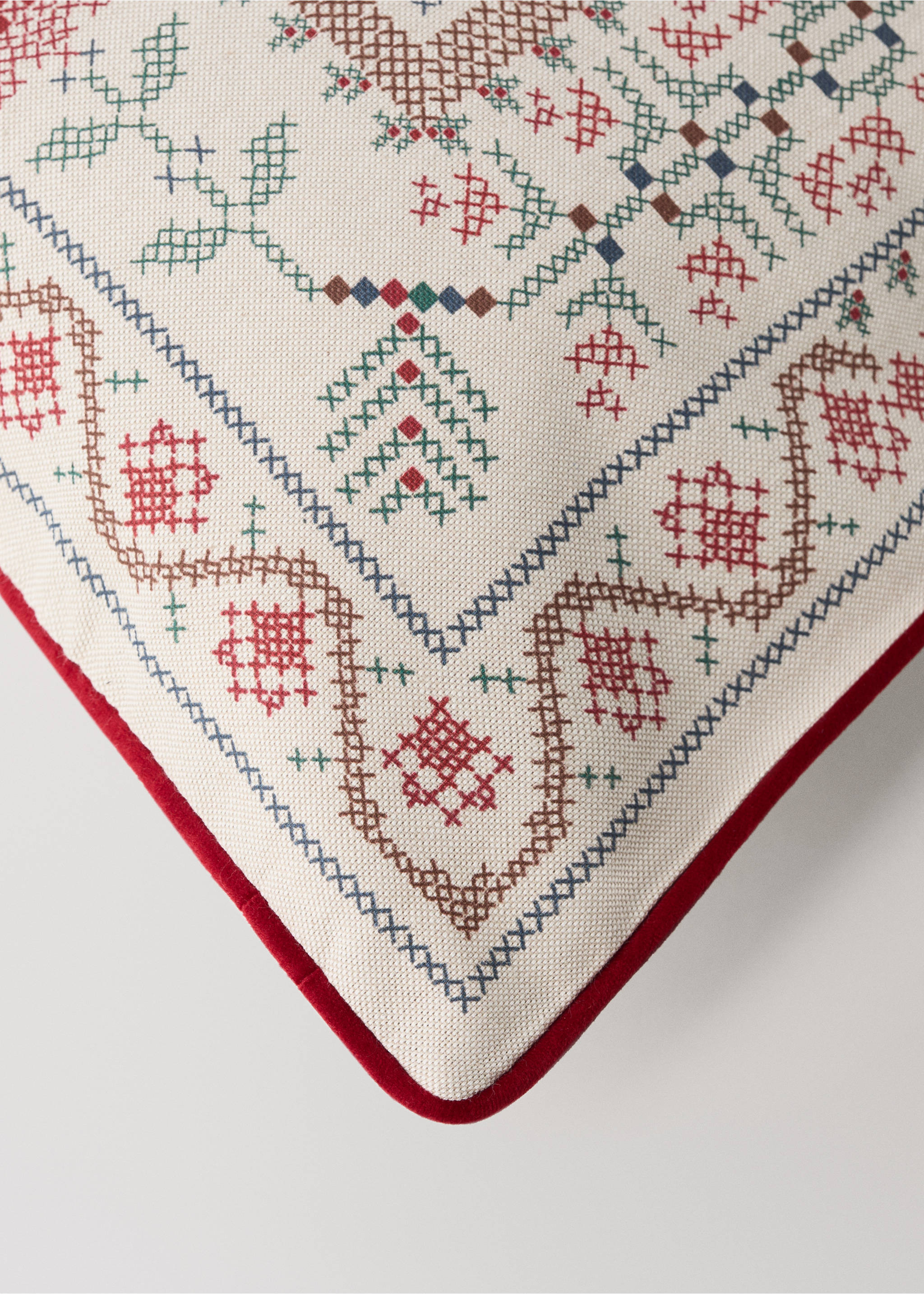 Close-up of a white cushion cover with geometric cross-stitch embroidery and red piping., Red. Ref: 37007936-00.