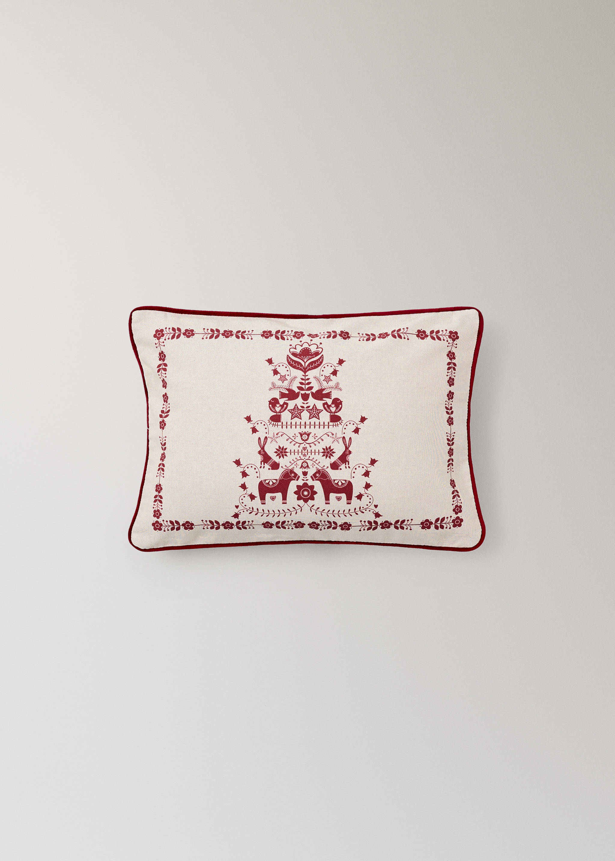 Off-white cushion cover featuring a dark red festive folkloric motif and piped edges.