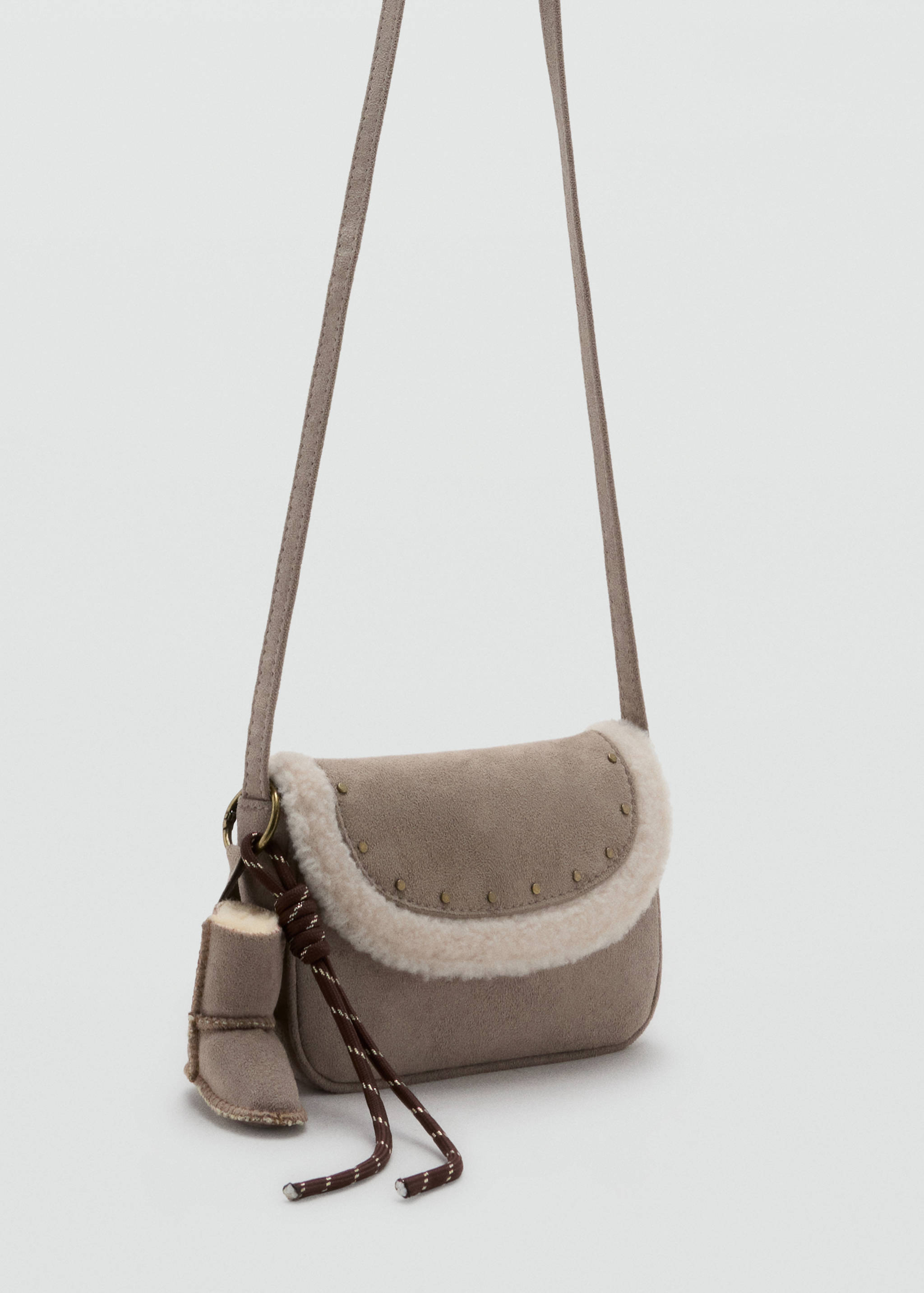 Grey mini crossbody bag with cream faux-shearling trim, stud details, and a miniature boot charm.