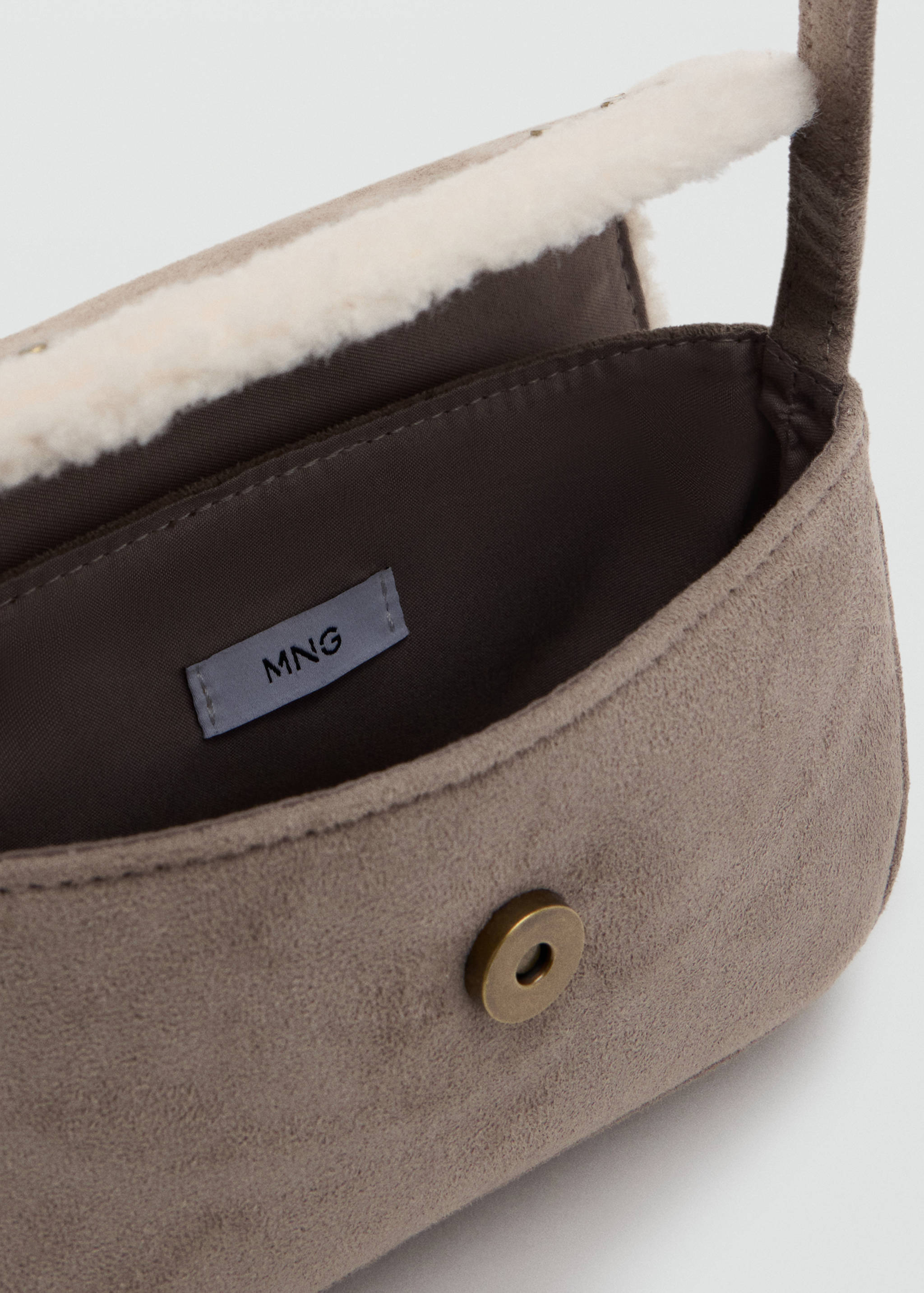 Close-up of a taupe mini bag with faux-shearling trim and snap closure.