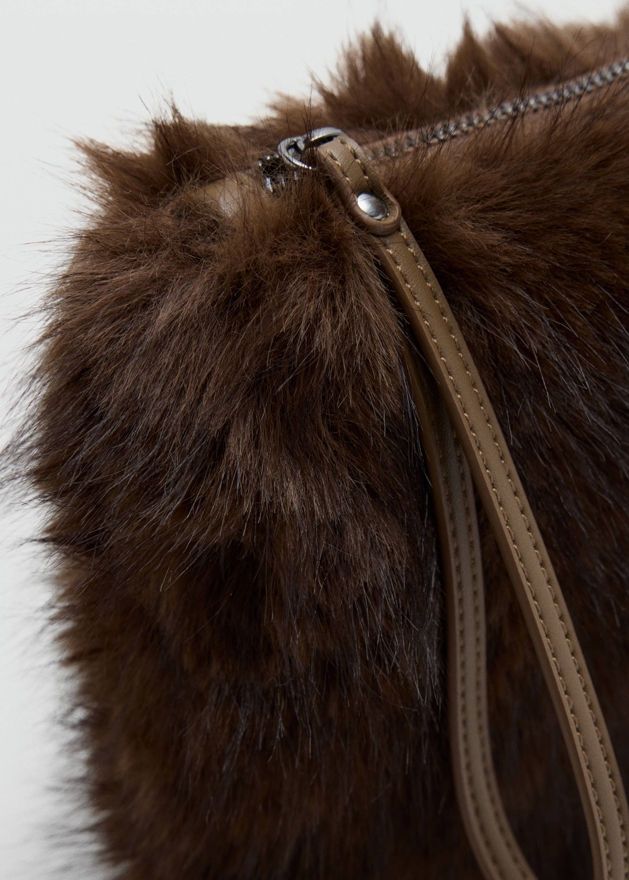 Close-up of a brown faux-fur mini bag showing the textured material and zip closure.