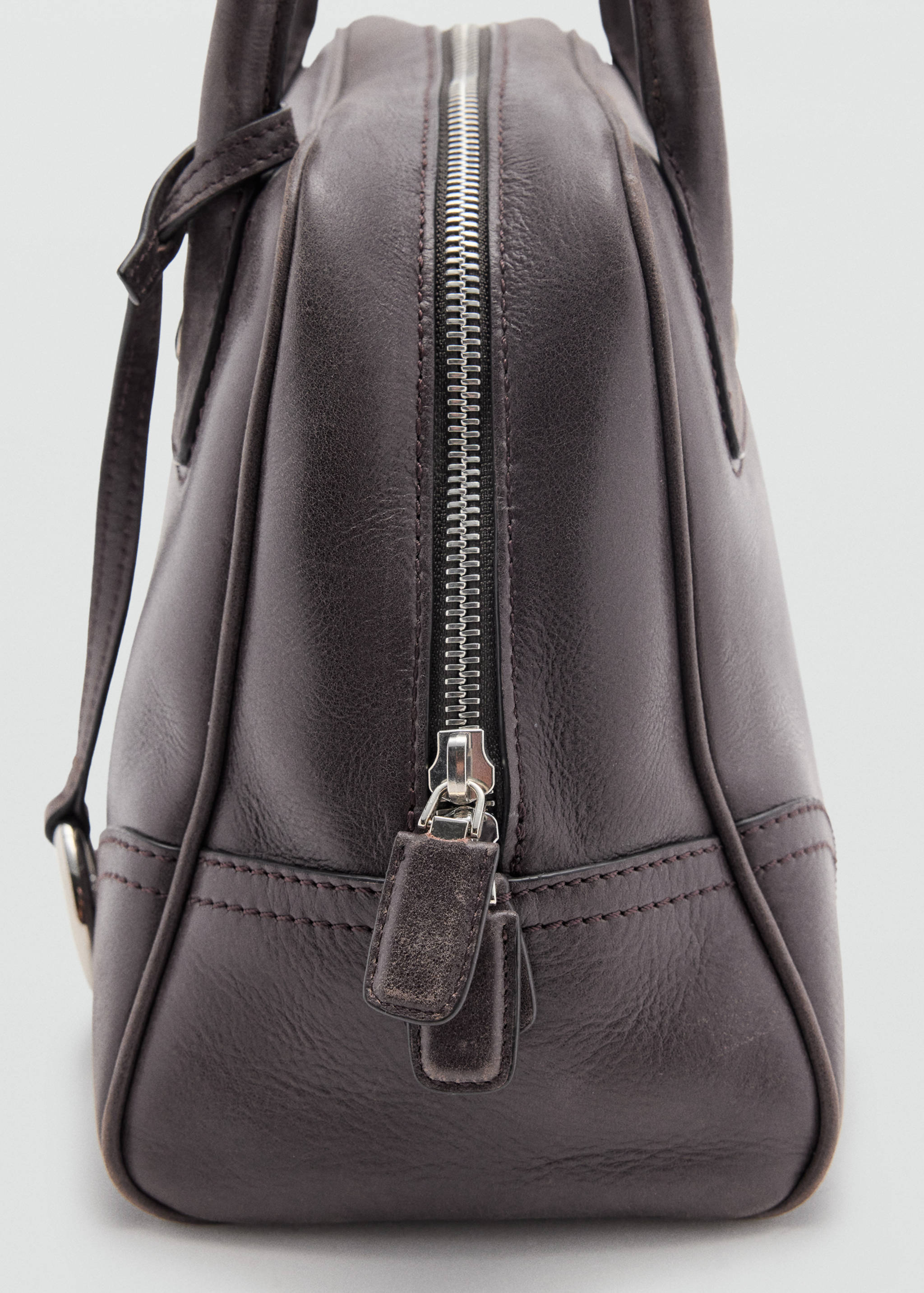 Close-up of zip closure and pull tabs on a dark brown bowling bag.