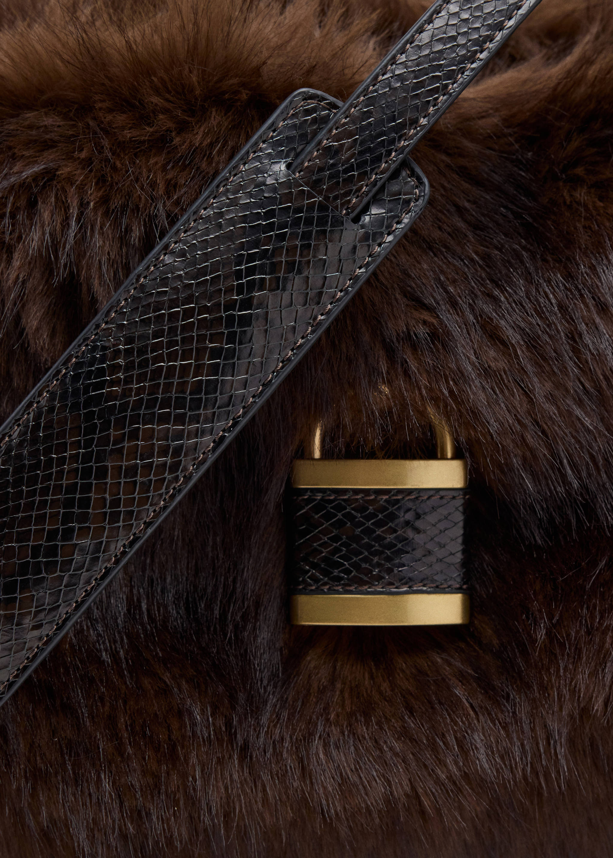 Close-up of a brown faux-fur shoulder bag with a snakeskin-effect strap and gold padlock.