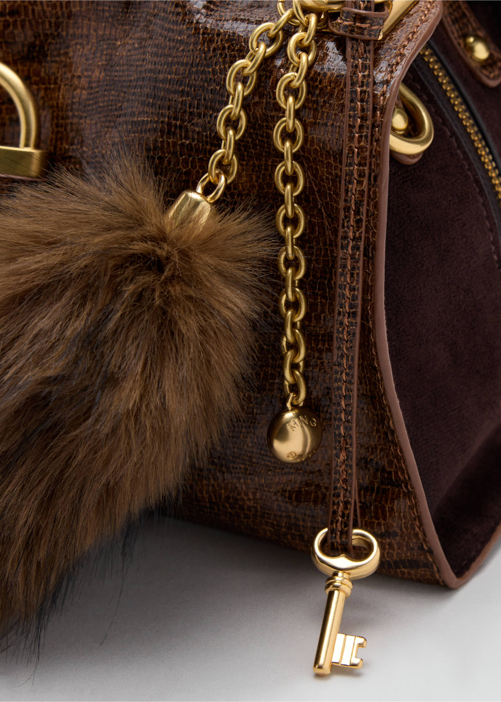Brown crossbody bag detail with faux-fur pom-pom, key charm and gold hardware., Leather. Ref: 37007947-00.