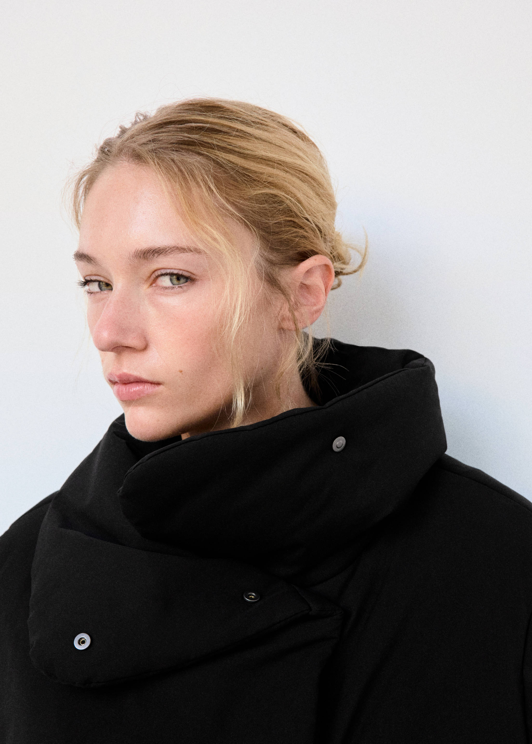 Black anorak with a high wrap collar and snap button detail.
