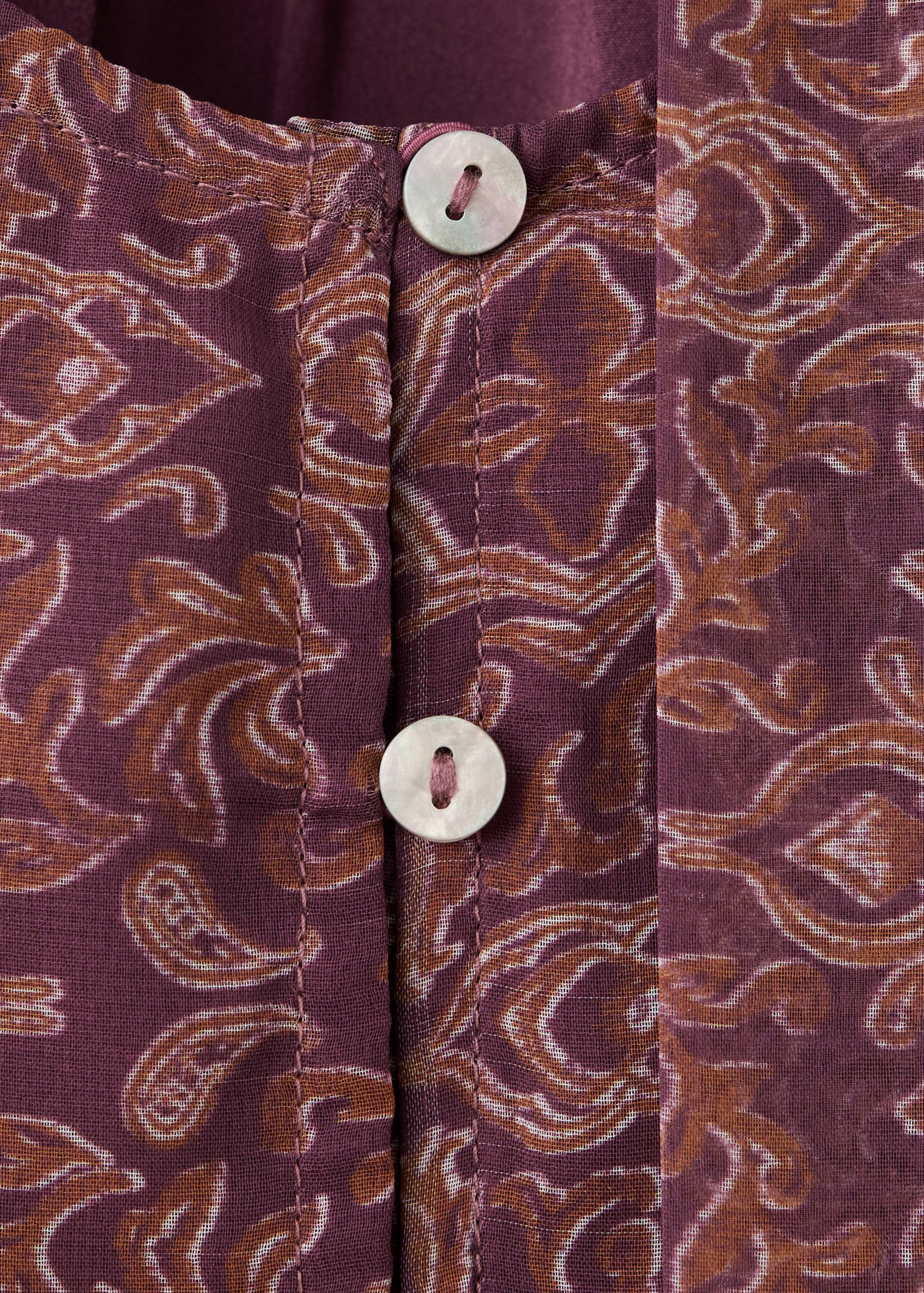 Plum printed shirt detail with paisley pattern and mother-of-pearl buttons.