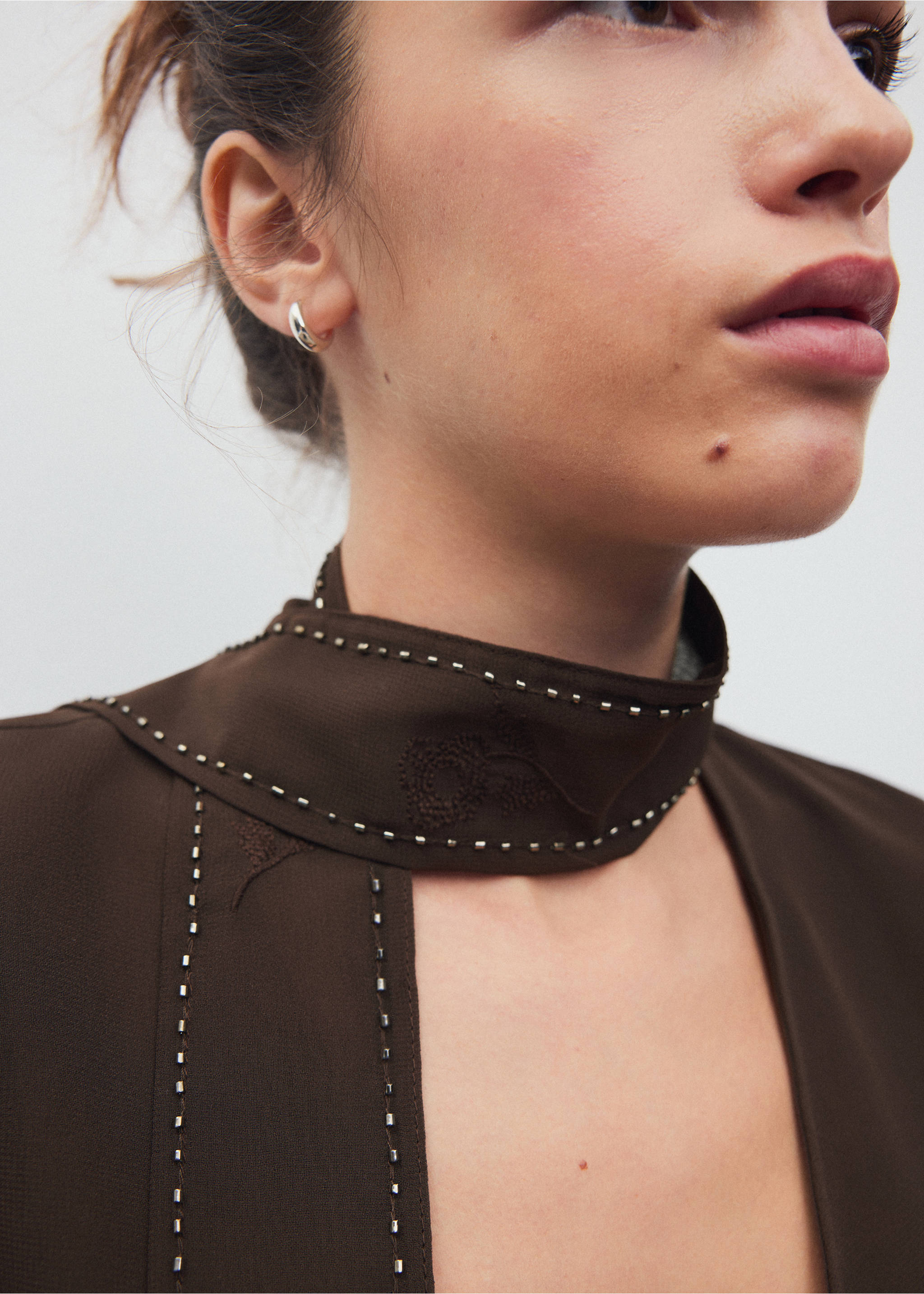 Close-up of a brown shirt with a studded high neckline., Brown. Ref: 37008281-00.