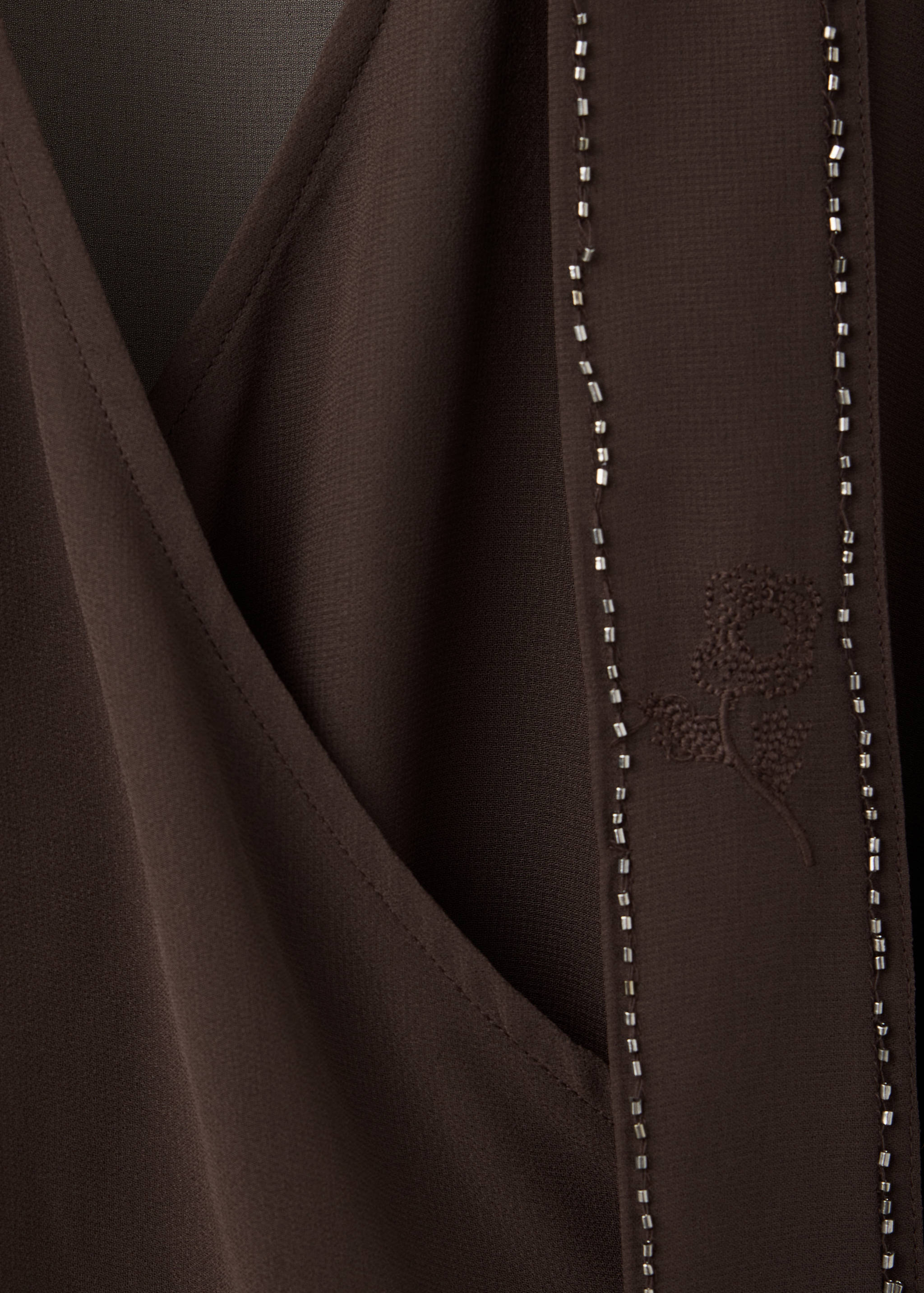 Dark brown wrap shirt with beaded strap and floral embroidery.