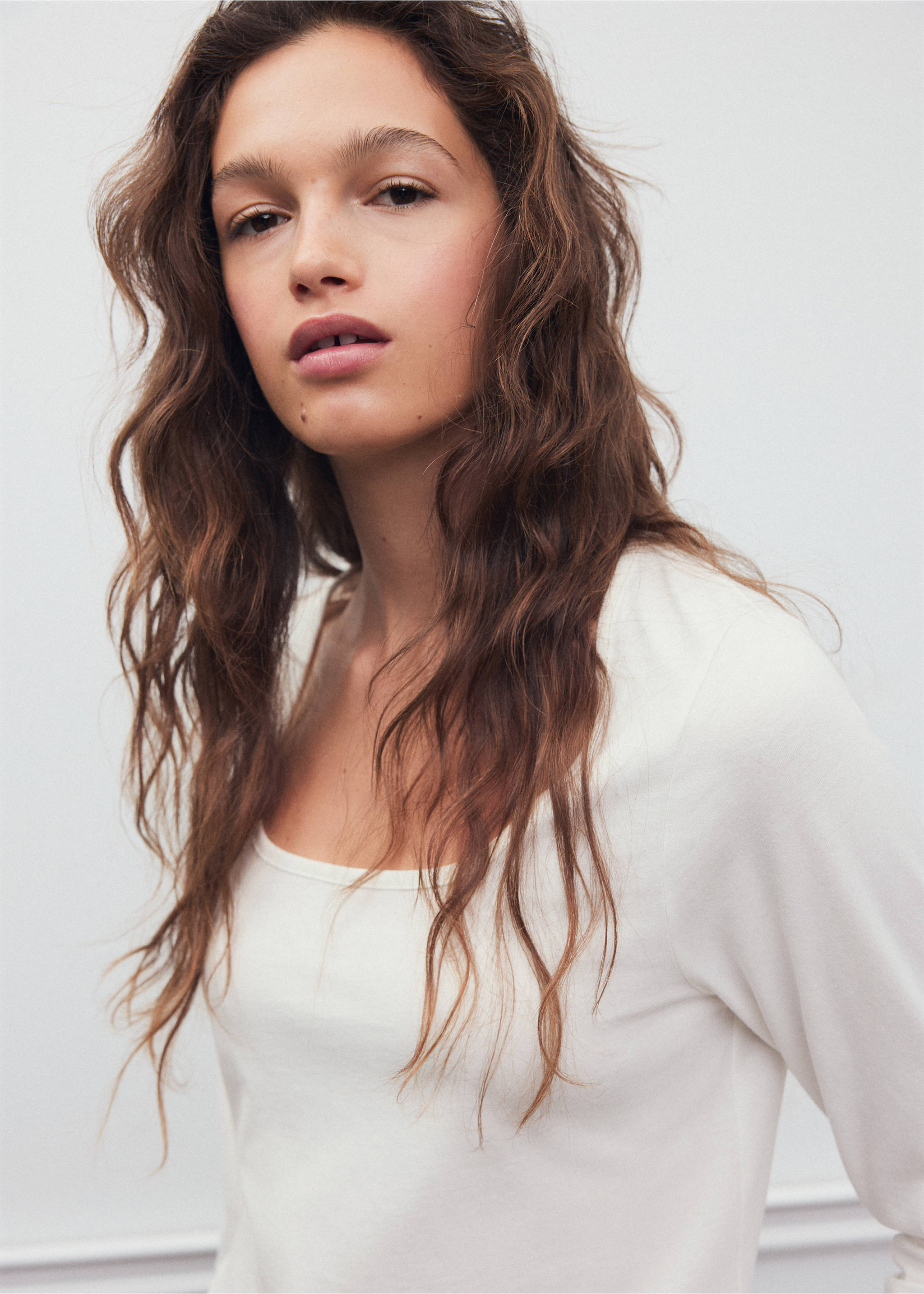 Close-up of a model wearing an off-white long-sleeved t-shirt with a scoop neck., Off White. Ref: 37008285-00.