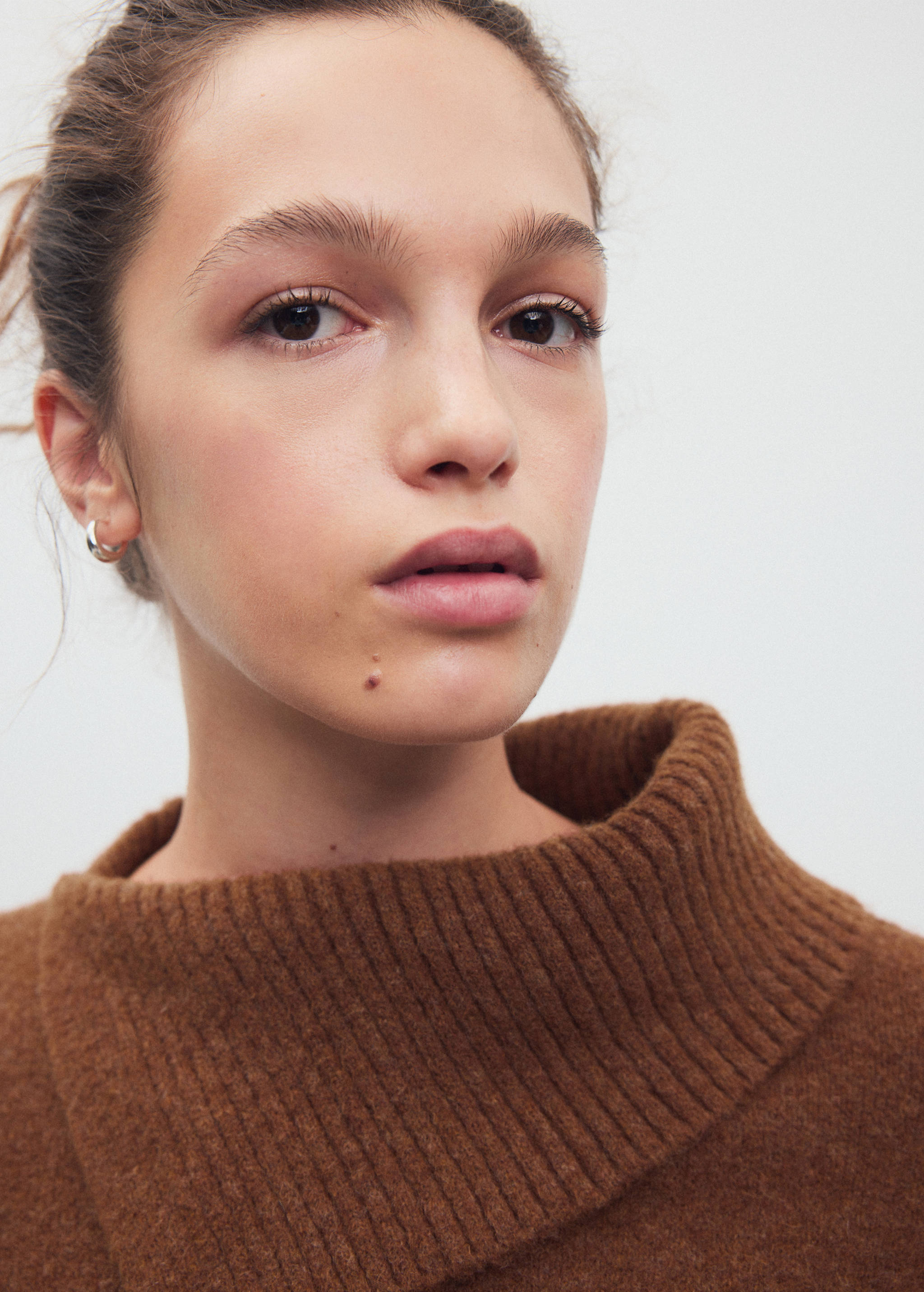 Brown knitted jersey featuring a wide, high ribbed turtleneck collar.