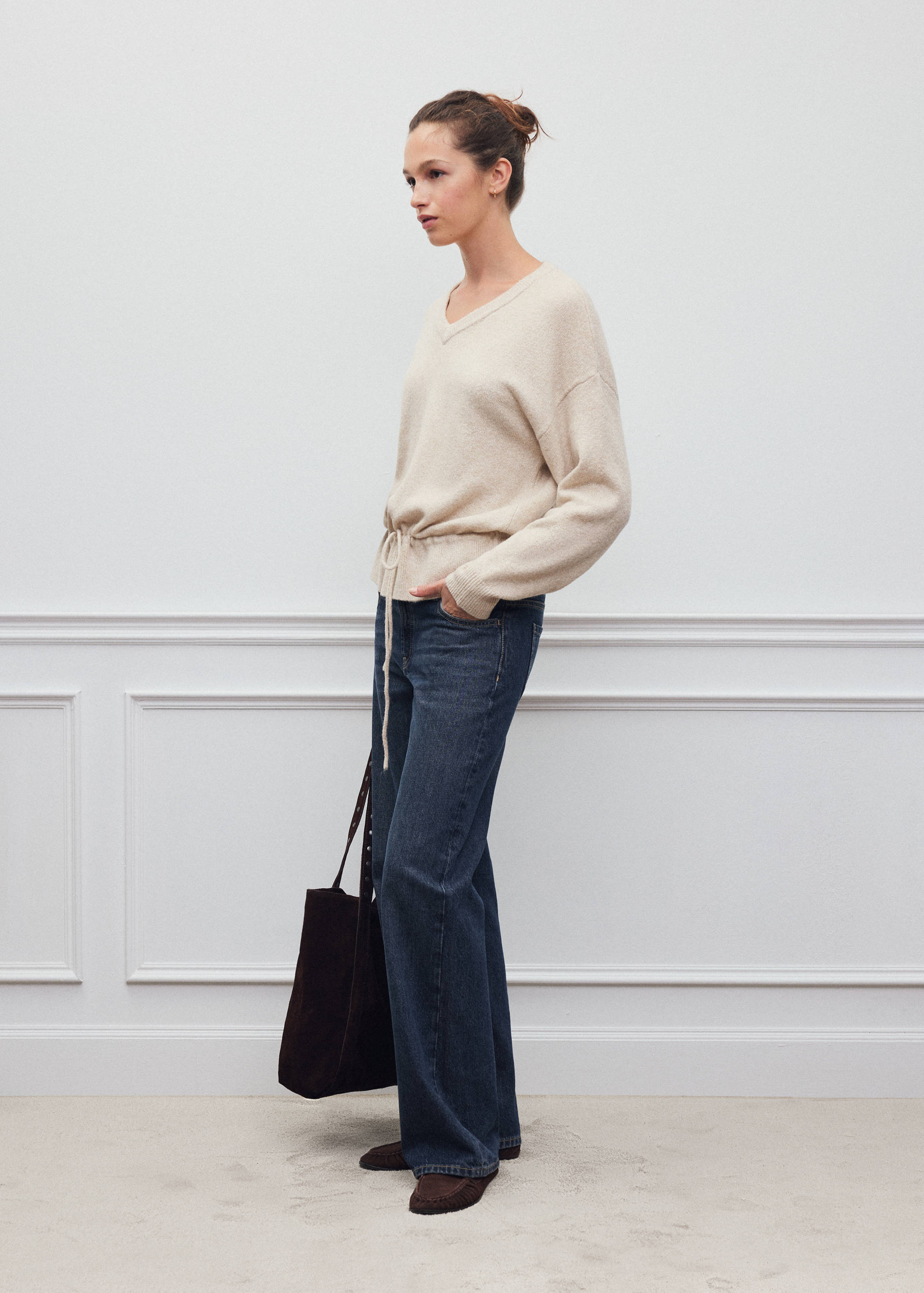 Cream V-neck jersey with a drawstring waist, worn with dark blue jeans.
