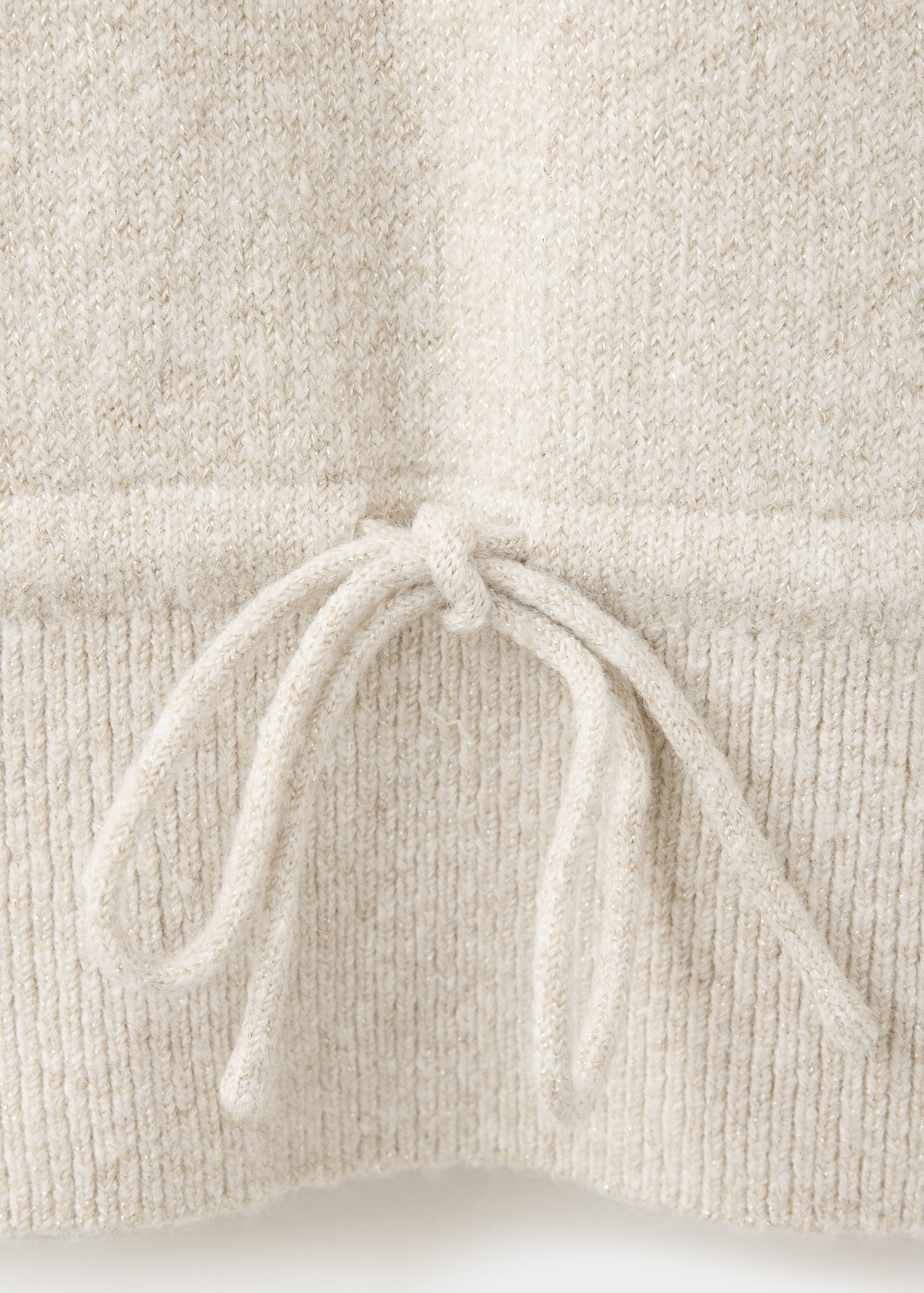 Close-up of a light beige knit jersey showing the fabric detail and drawstring waist.