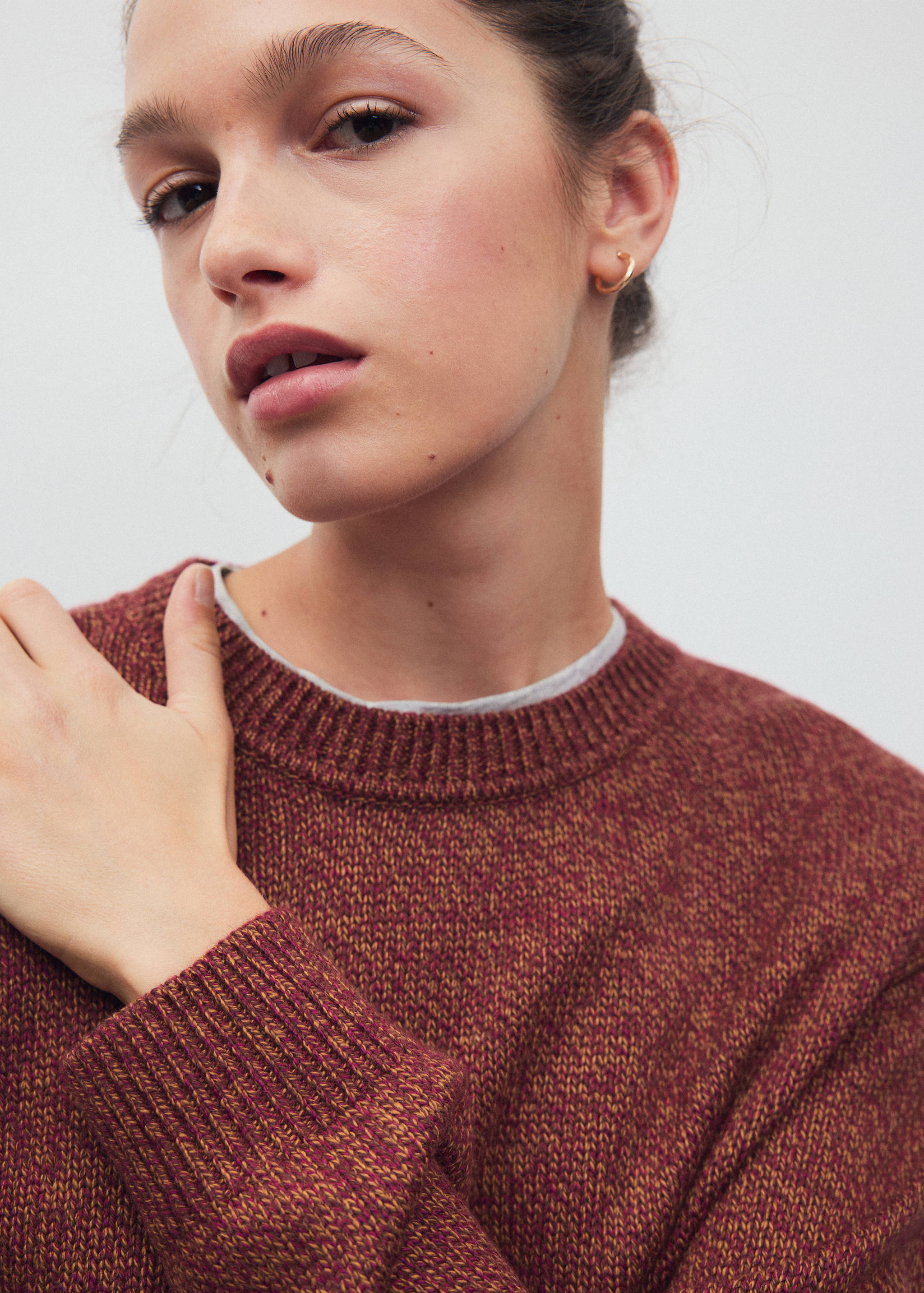 Close-up of a maroon and yellow knitted jumper with a crew neck.