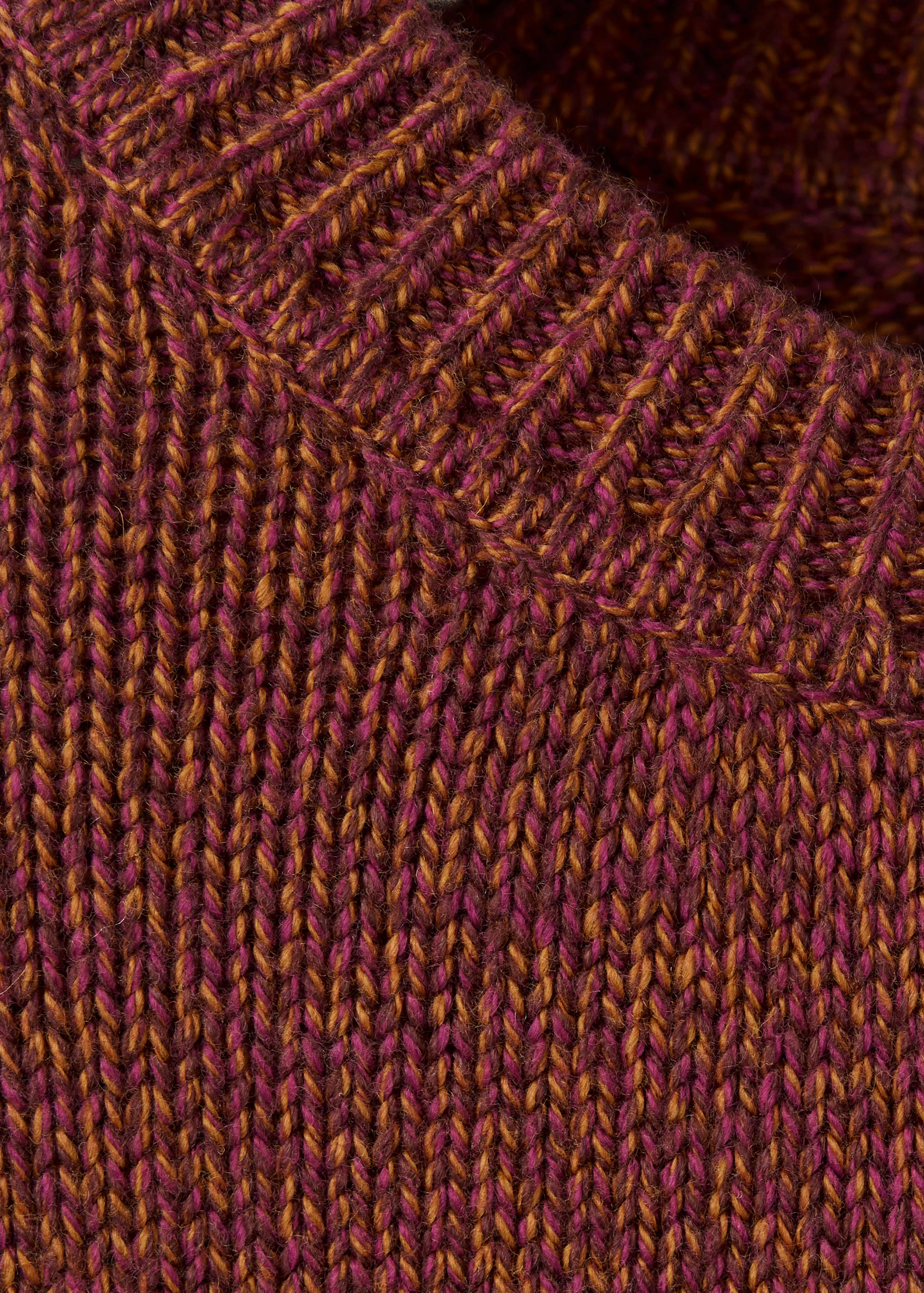 Close-up of a magenta and ochre marled knit jersey showing its ribbed texture.