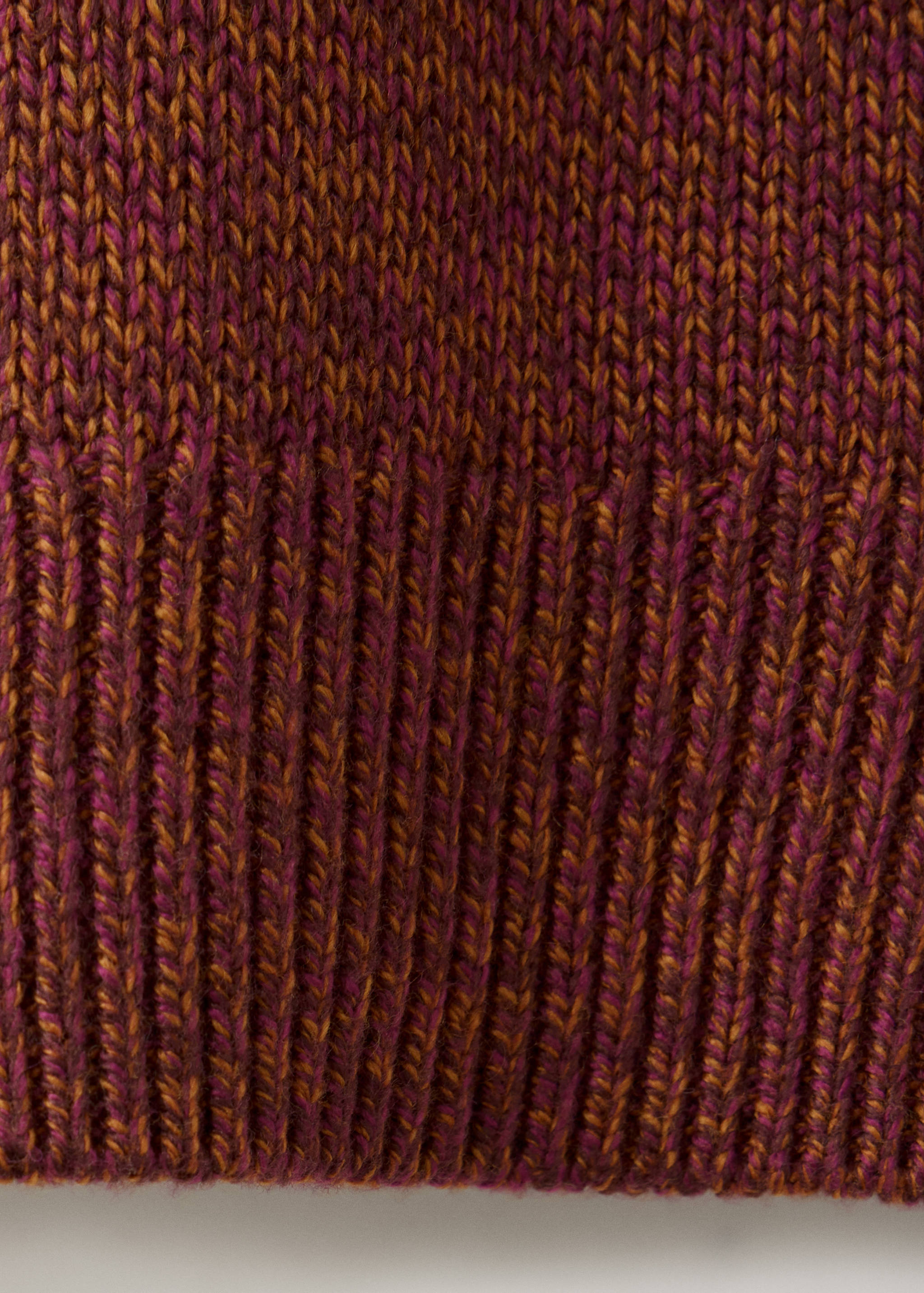 Close-up of the knitted jersey fabric texture in magenta and mustard yellow.