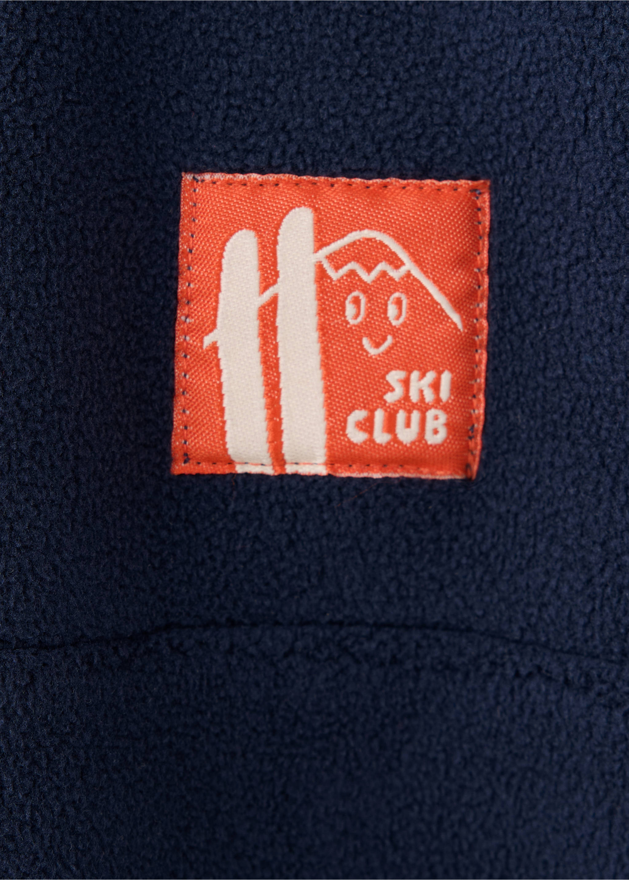 Close-up of a navy fleece sweatshirt with a Ski Club patch., Russet. Ref: 37008637-00.