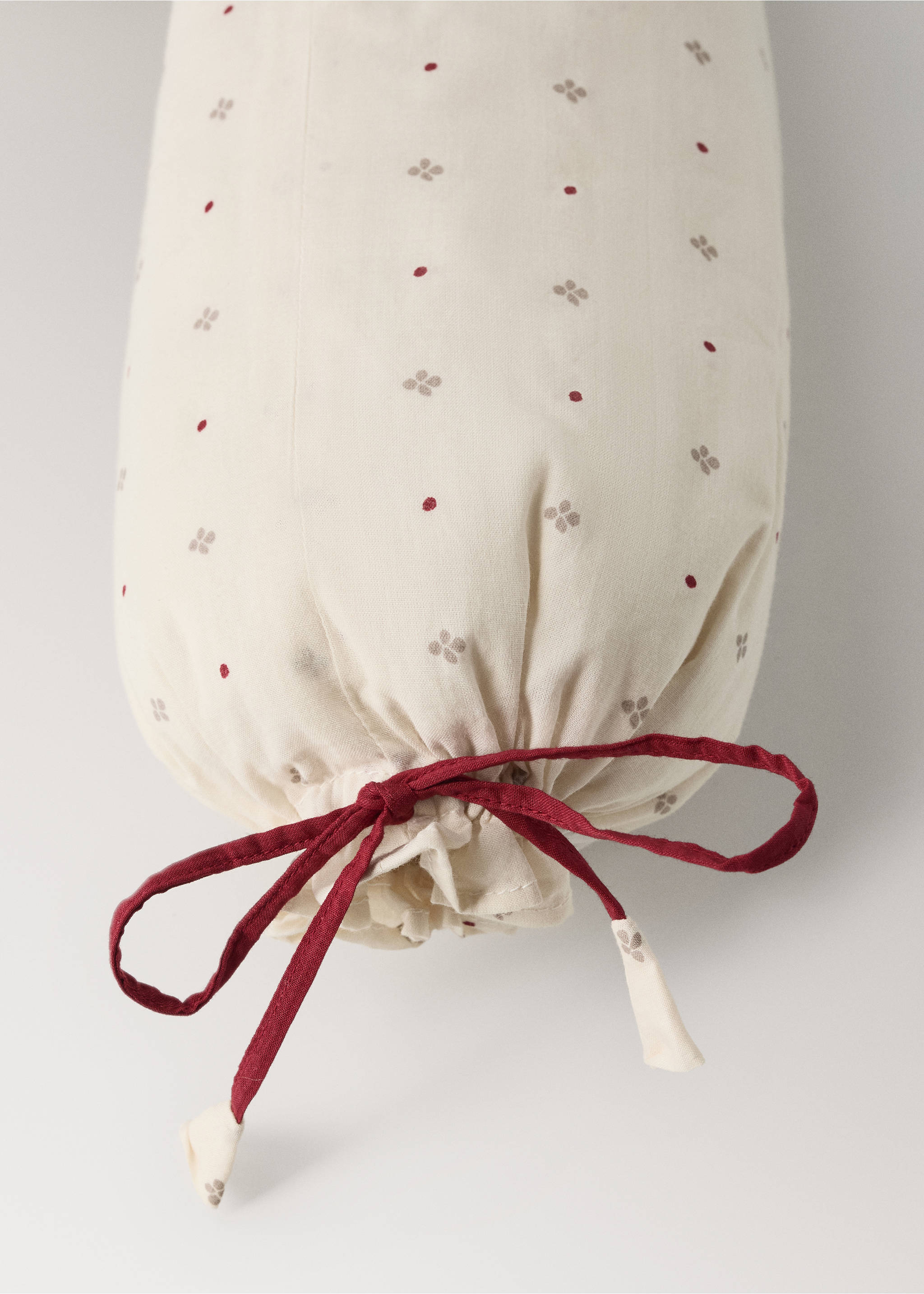 Printed cylindrical cushion in cream with a red ribbon tie detail., Red. Ref: 37008638-00.