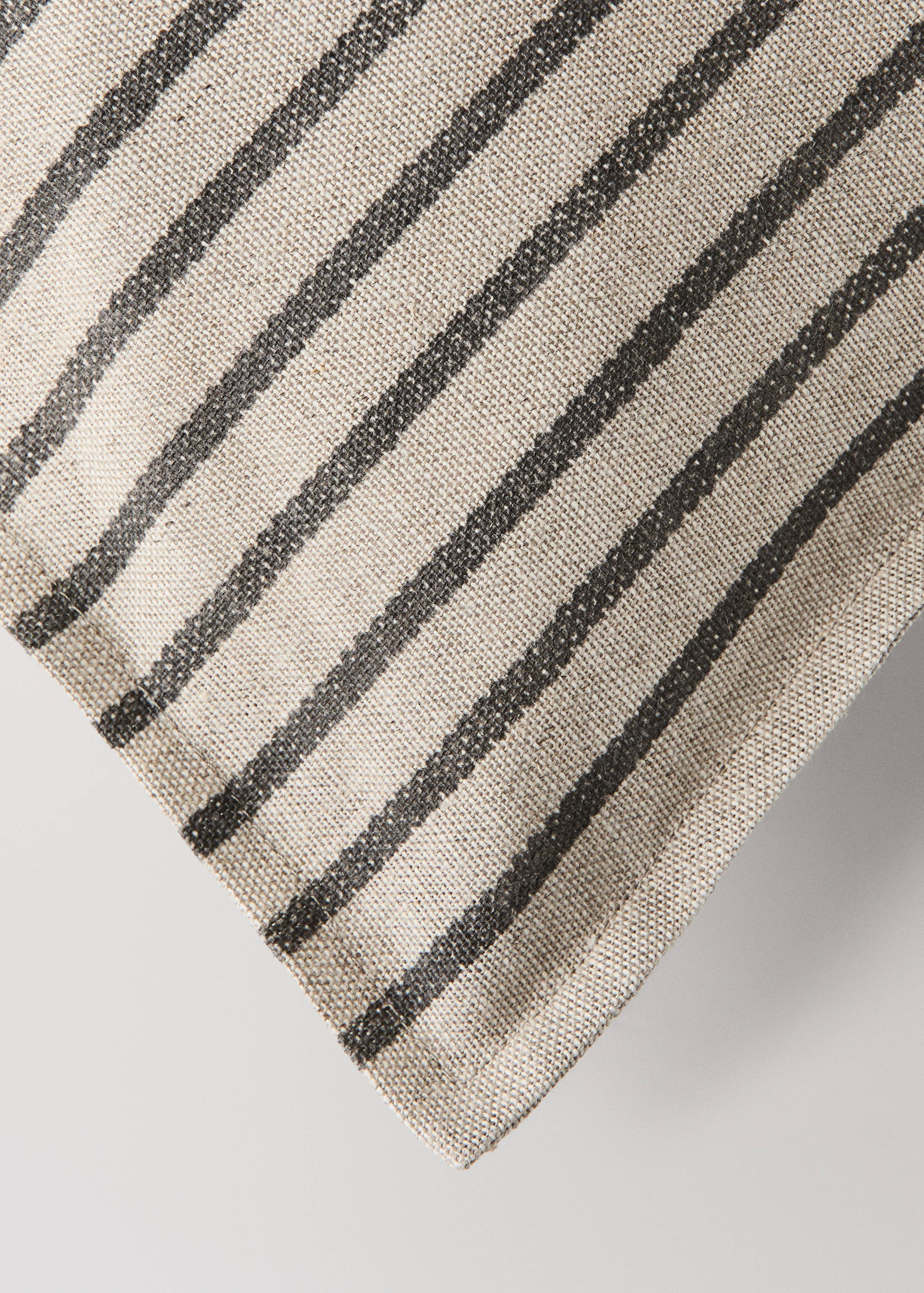 Close-up of a textured beige cushion cover with diagonal dark grey stripes.