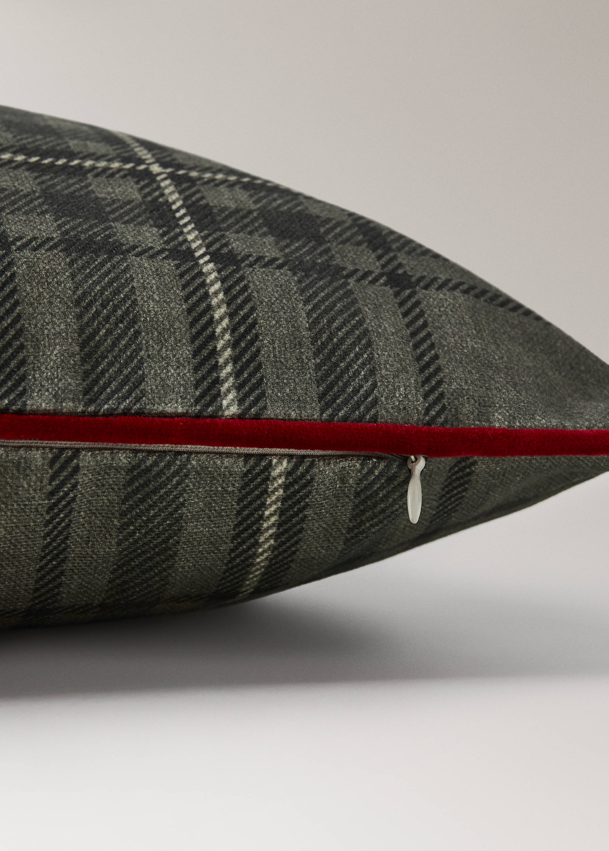 Green tartan cushion cover with red velvet piping and zipper detail.