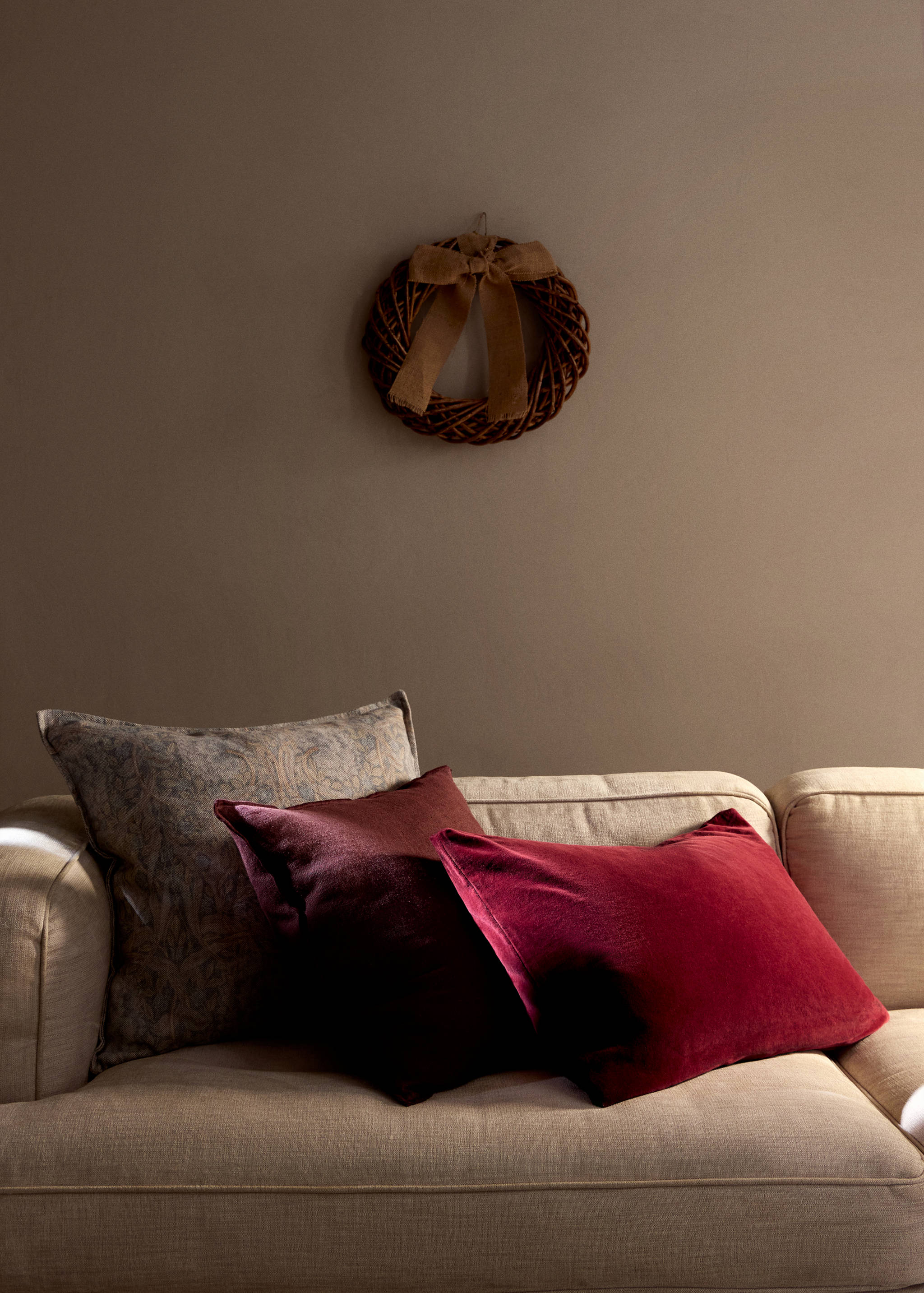 Deep red velvet cushion cover on a beige sofa.