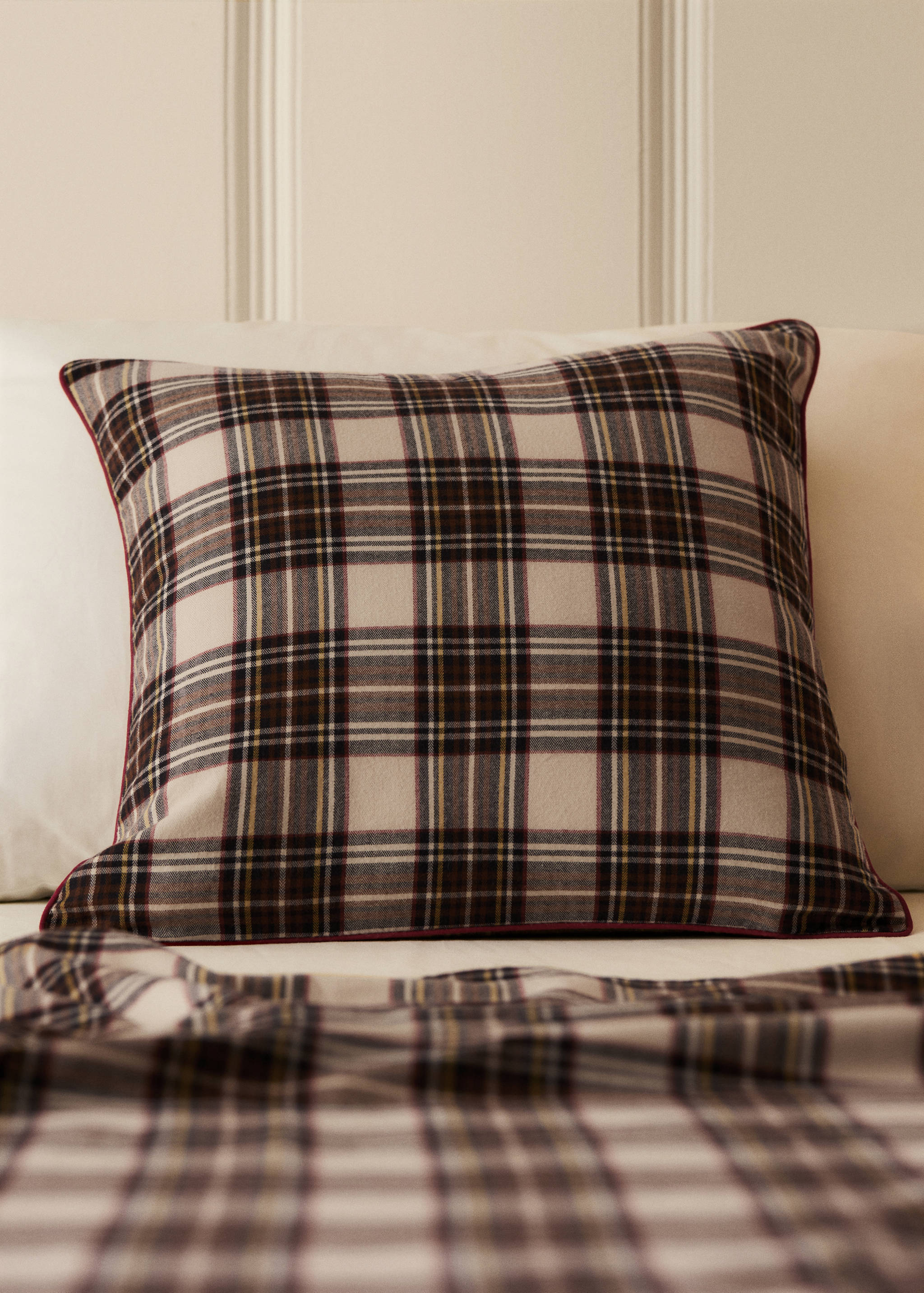 Beige, black and red plaid cushion cover with red piping.